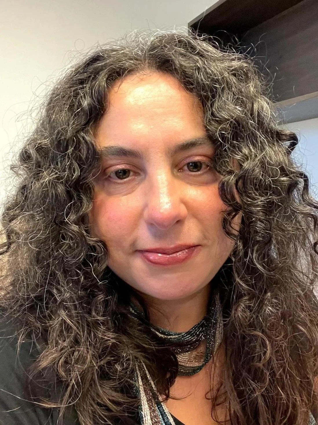 A close-up photo of a woman with curly brown hair and a friendly expression.