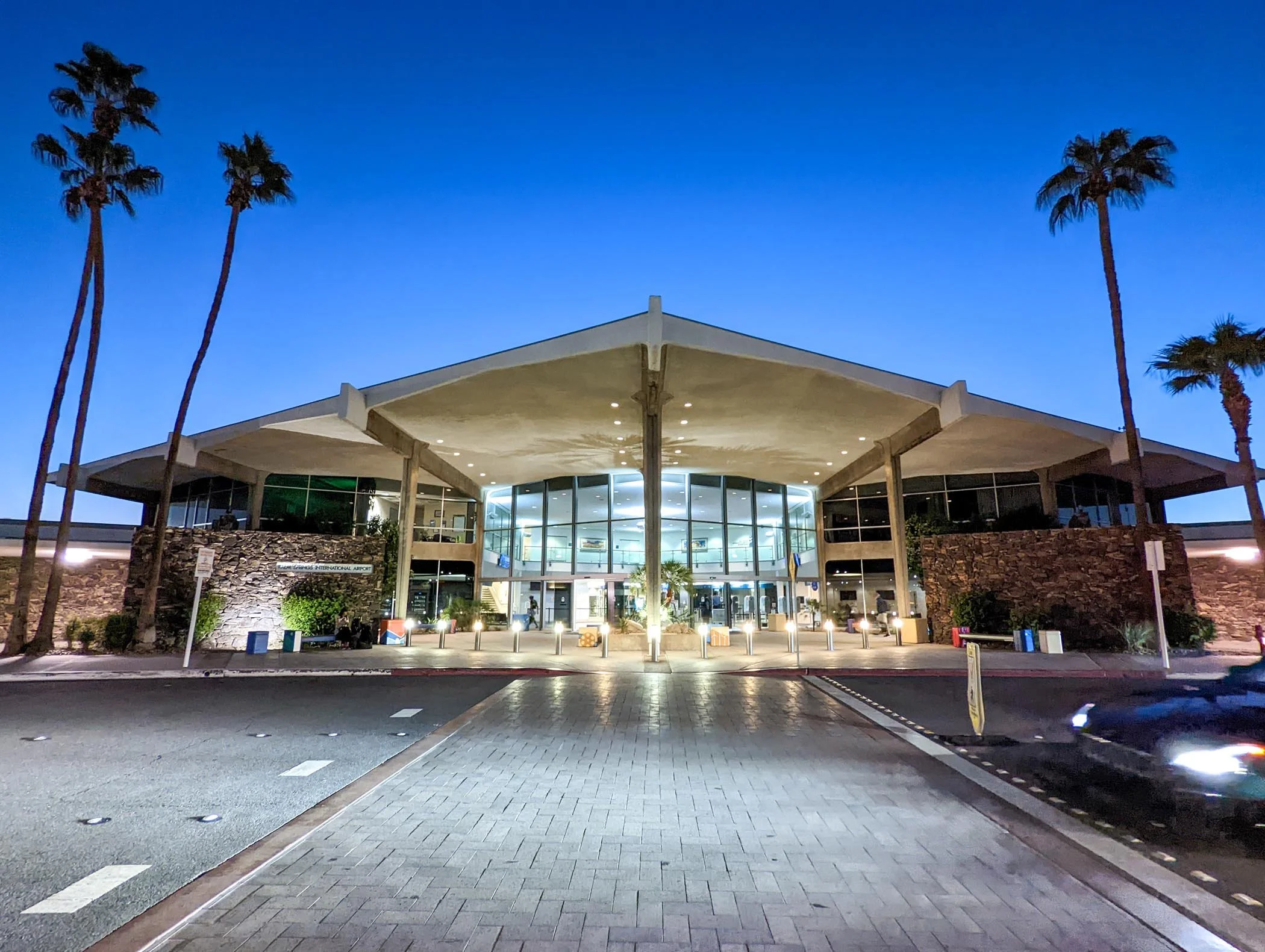 Nighttime exterior view of Long Beach International Airport with palm trees and a modern building entrance.