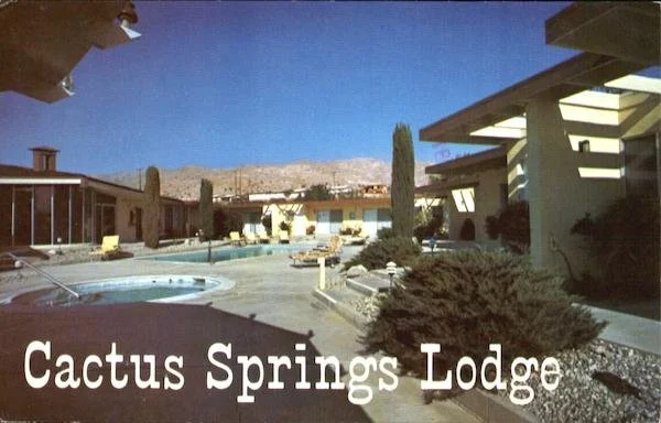 An outdoor scene of a motel called Cactus Springs Lodge with a swimming pool, cacti, and desert mountains in the background.