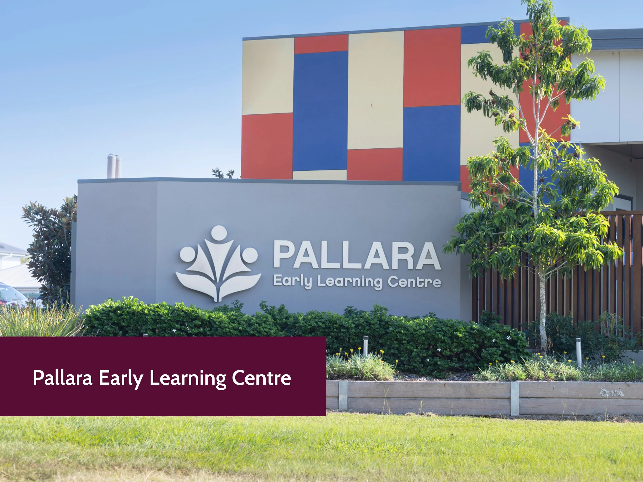 Exterior sign for Pallara Early Learning Centre with colorful geometric-patterned wall and landscaping in the foreground.