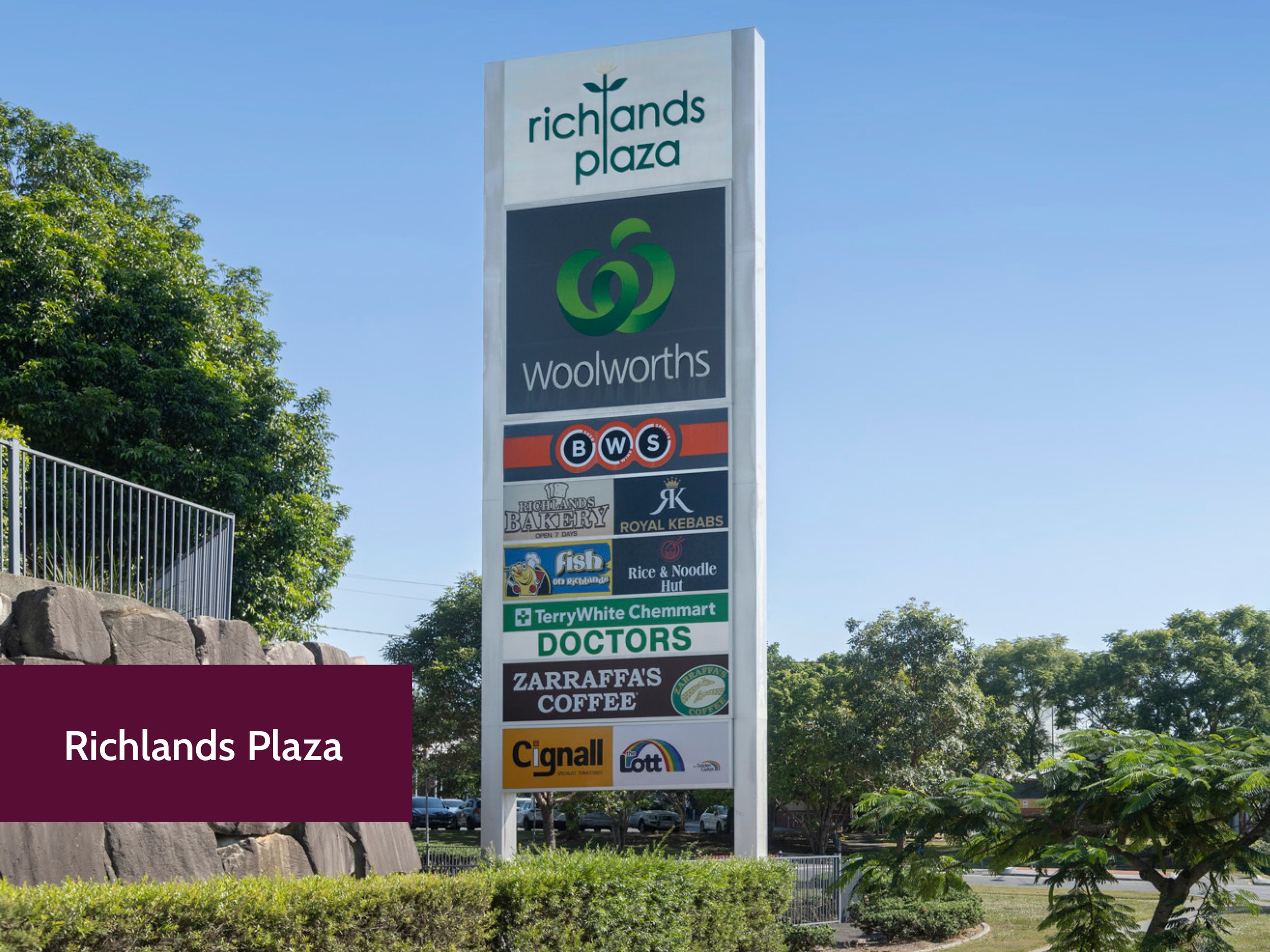 A tall sign at Richlands Plaza displays logos and names of various stores and businesses, including Woolworths, BWS, Richlands Bakery, Royal Kebabs, Fish on Richlands, Rice & Noodle Hut, TerryWhite Chemmart, Doctors, Zarrafas Coffee, Cignal, and Lott