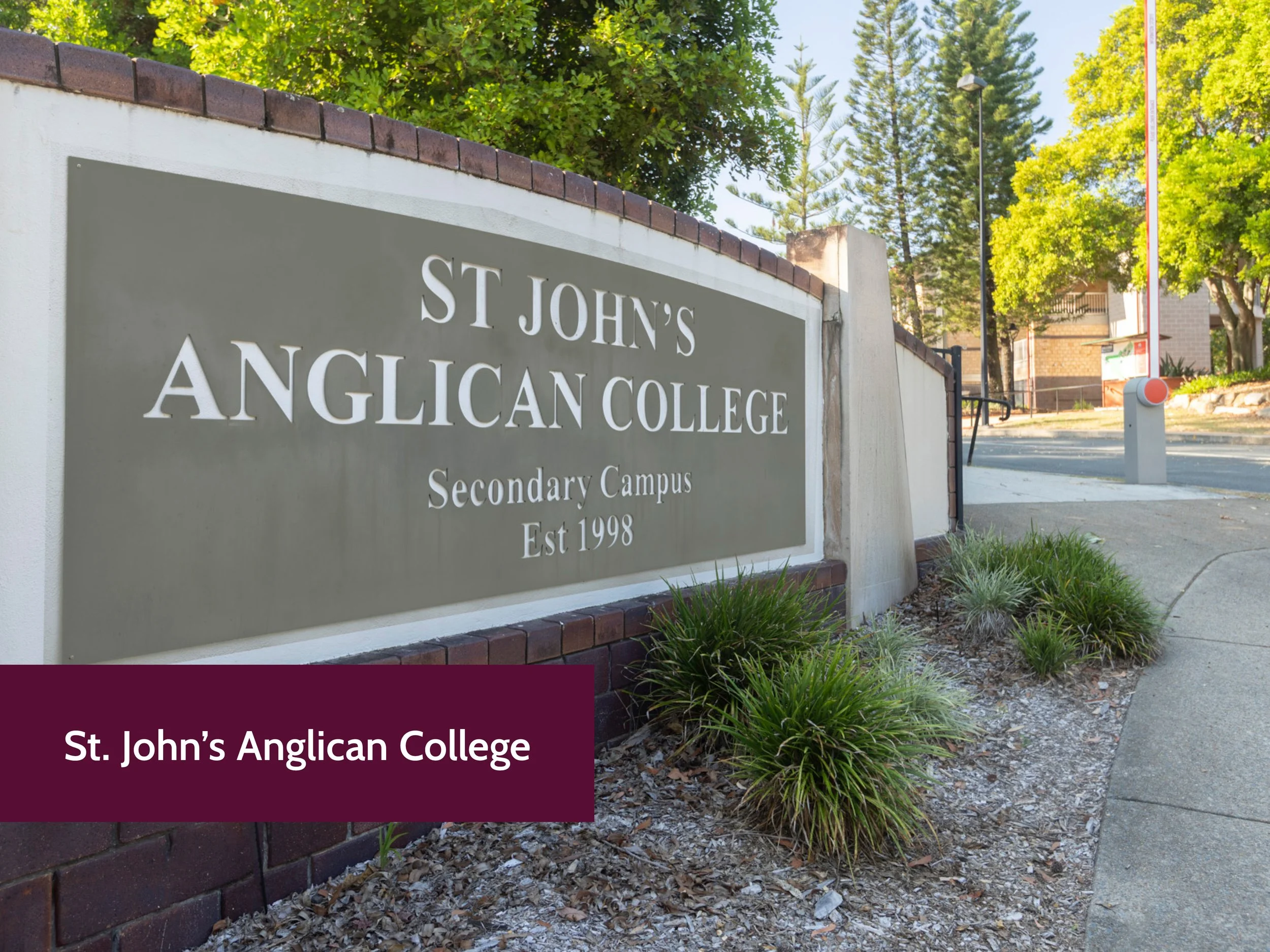 Photo of a sign at St. John's Anglican College, a secondary campus established in 1998, with trees and a street in the background.