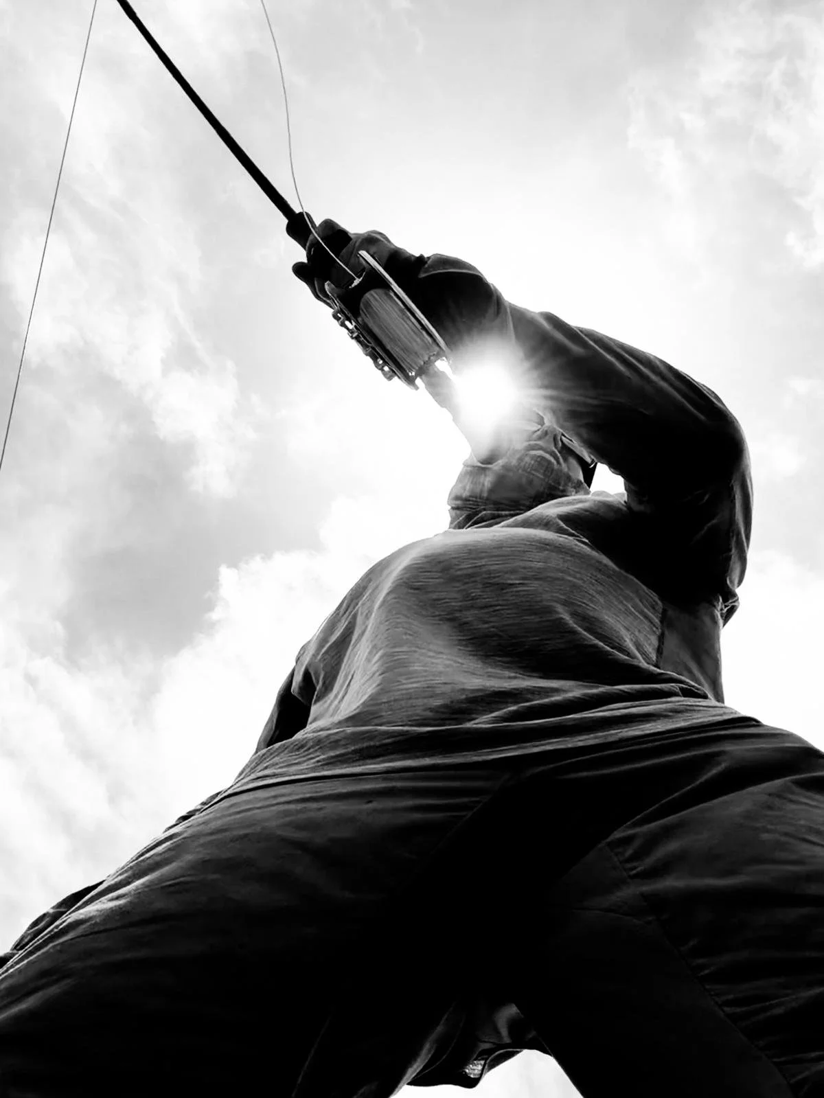 Black-and-white view of a fly angler casting into the light