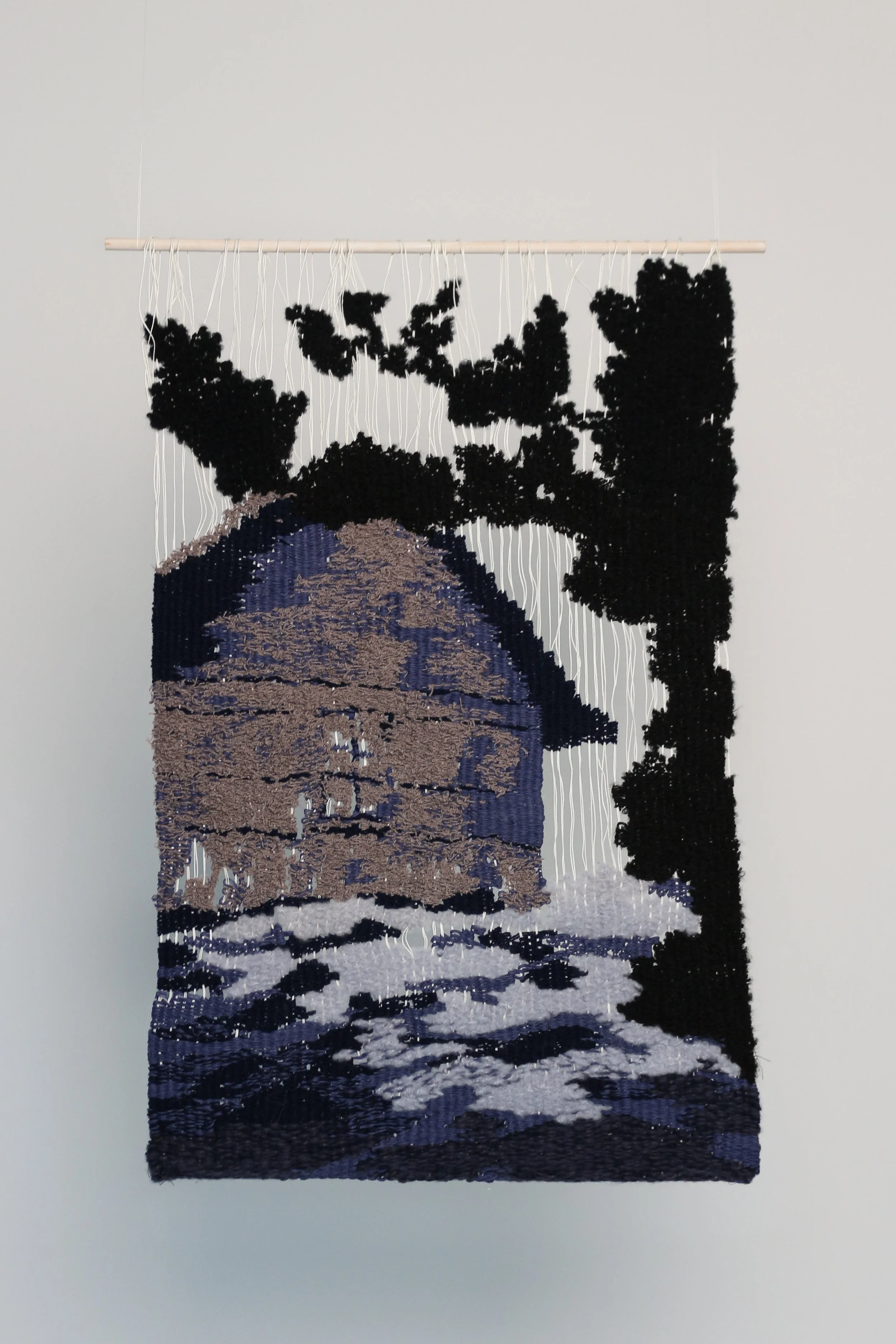 A textile art piece depicting a stylized image of a Landscape of the sea, an abandoned house and an abstract tree form.