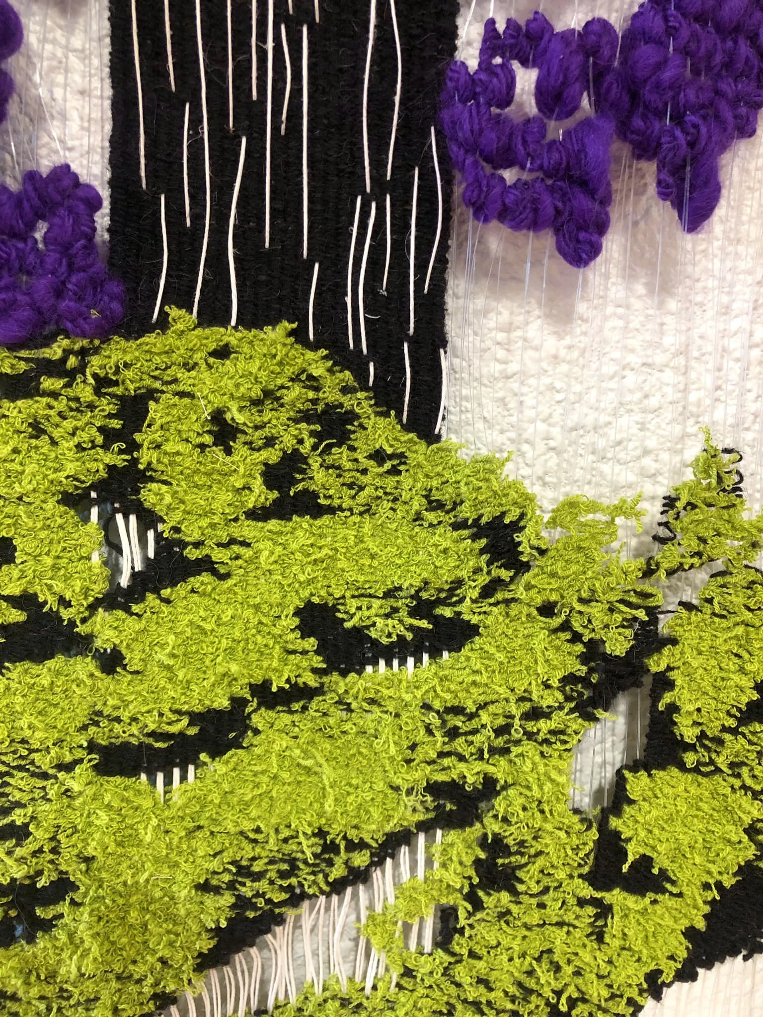 A fiber wall installation with purple, black, and lime green shapes.
