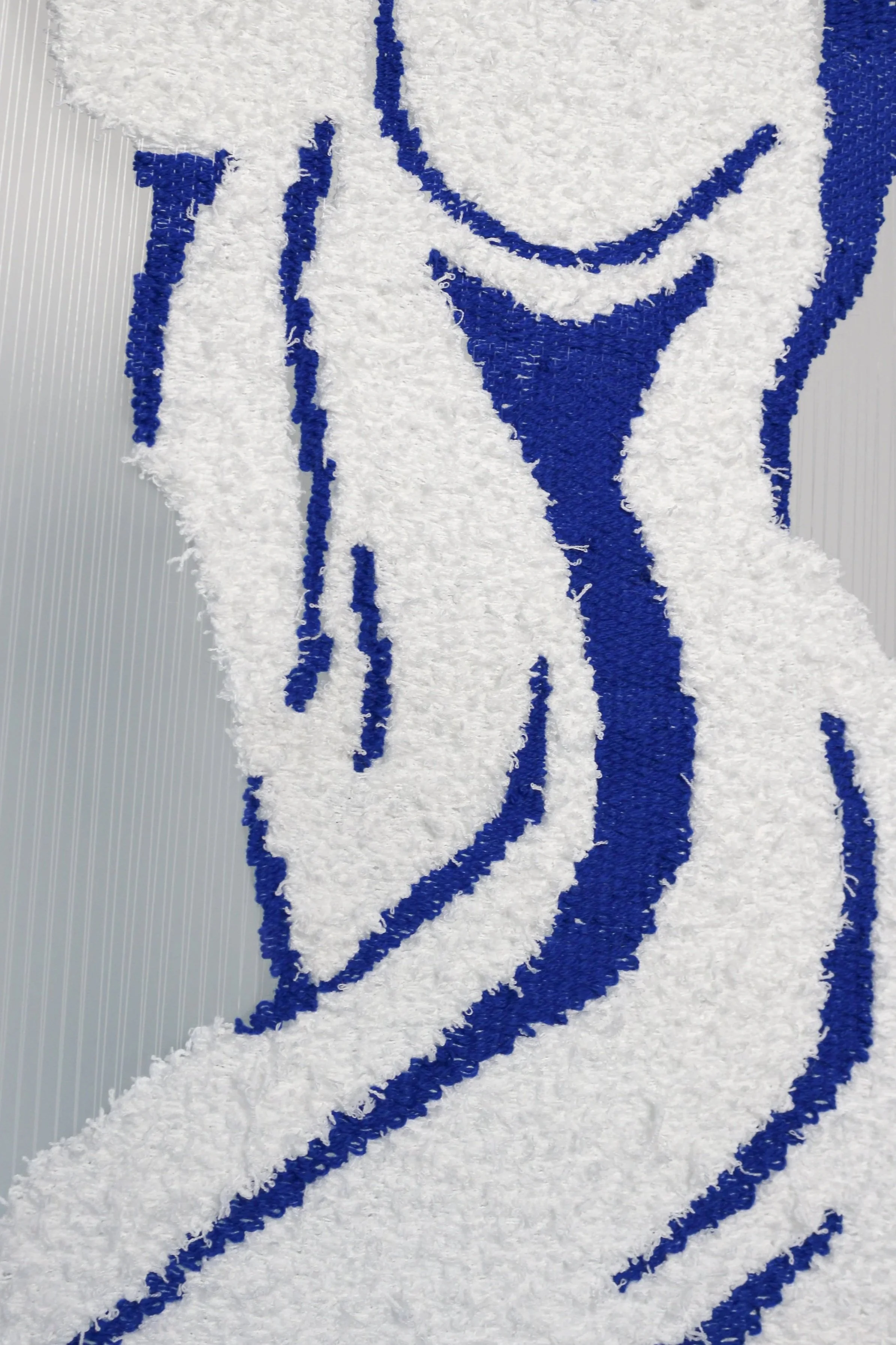Close-up of a textured art piece with blue and white fluffy yarn