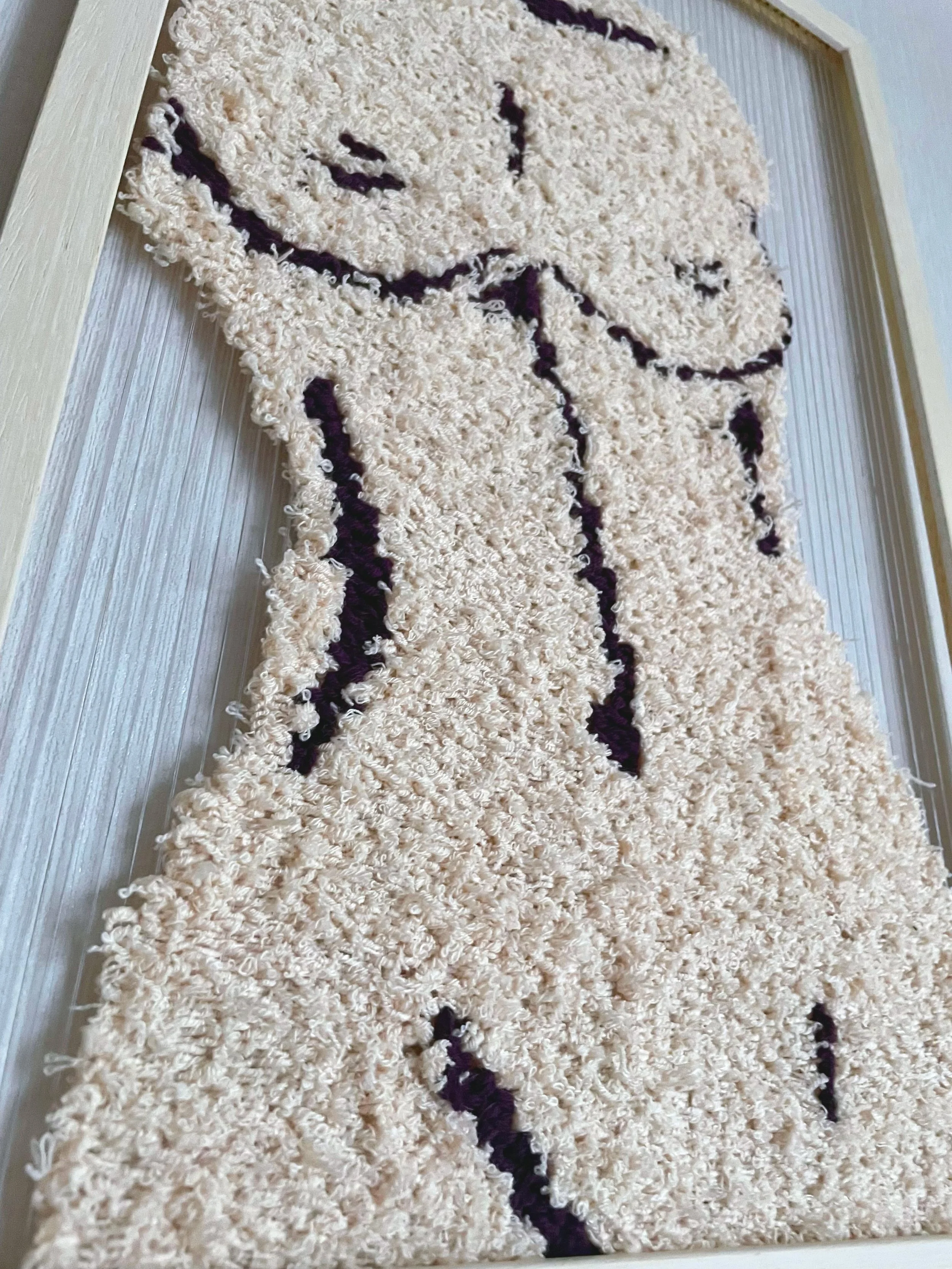 A rectangular shaggy rug with a cream background and purple flower design, placed on a light wood floor.
