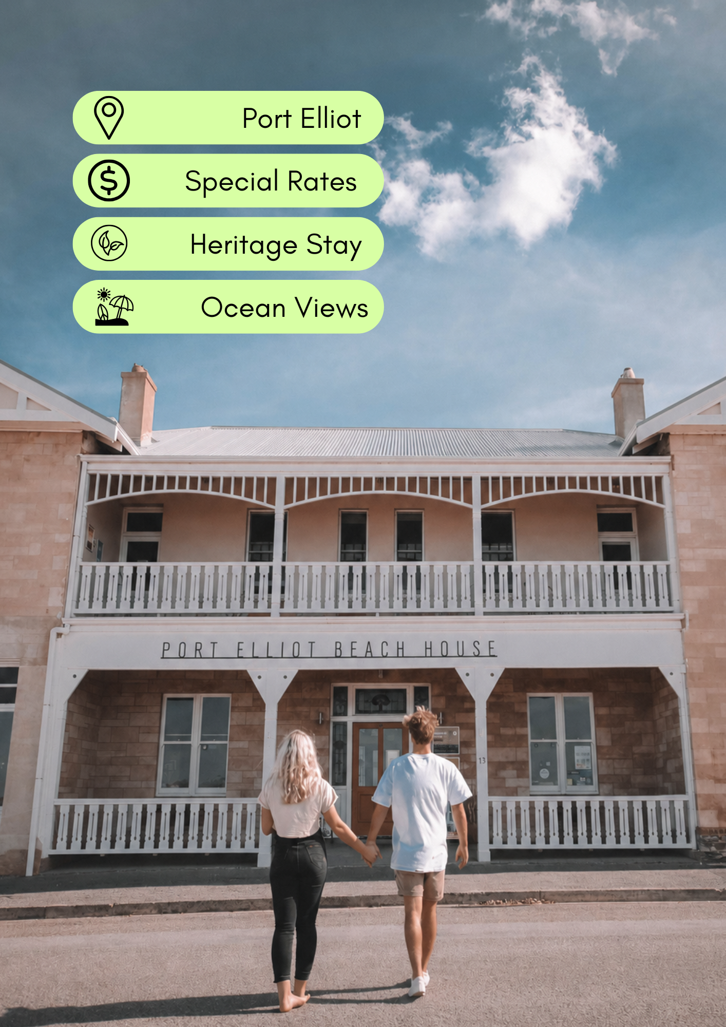 A couple holding hands and walking towards the Port Elliot Beach House on a sunny day. The building has a white porch with a sign that reads "Port Elliot Beach House."