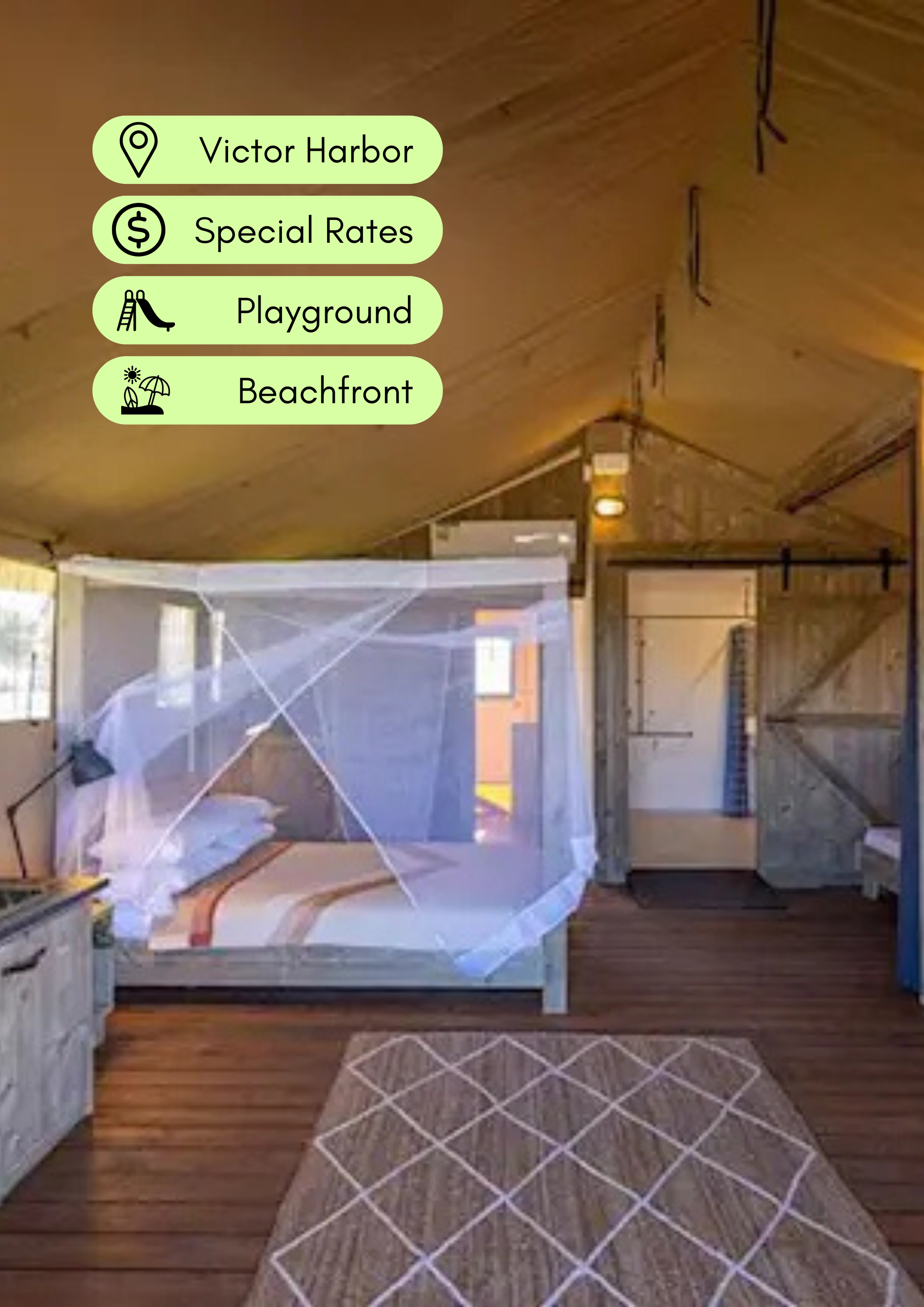 Interior of a house under construction with a kitchen on the left, a doorway in the center, and a partially built room on the right. There is a baby crib covered with a netted canopy in the foreground, a patterned rug on wooden flooring, and light-colored curtains on the window. Overhead, there are four green icons with black text indicating nearby locations: Victor Harbor, Special Rates, Playground, and Beachfront.