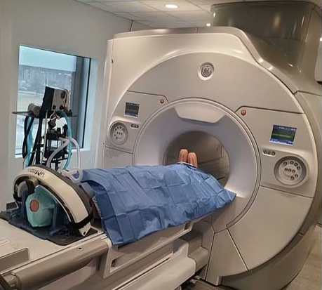 Patient lying on a hospital bed preparing for an MRI scan in a medical imaging room.