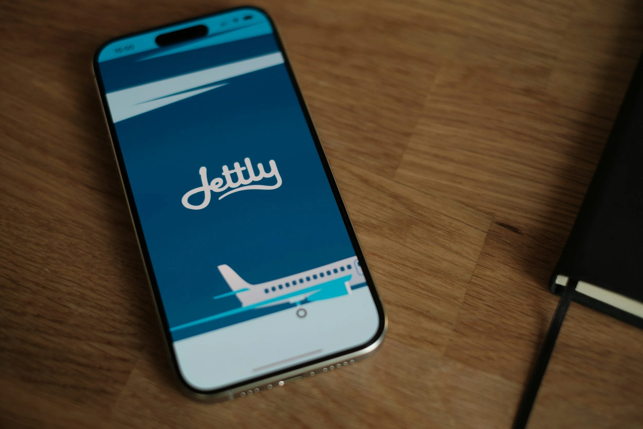 Smartphone displaying the Jetty app logo on a wooden surface.
