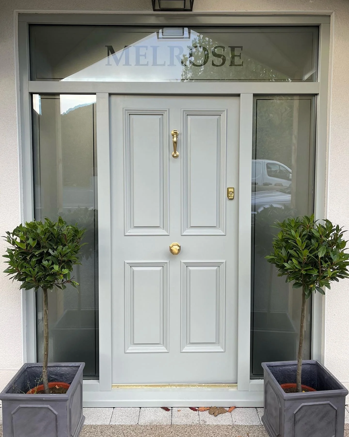 Front door with two potted trees on either side, and a sign above the door that says 'MELROSE'. in llandudno 