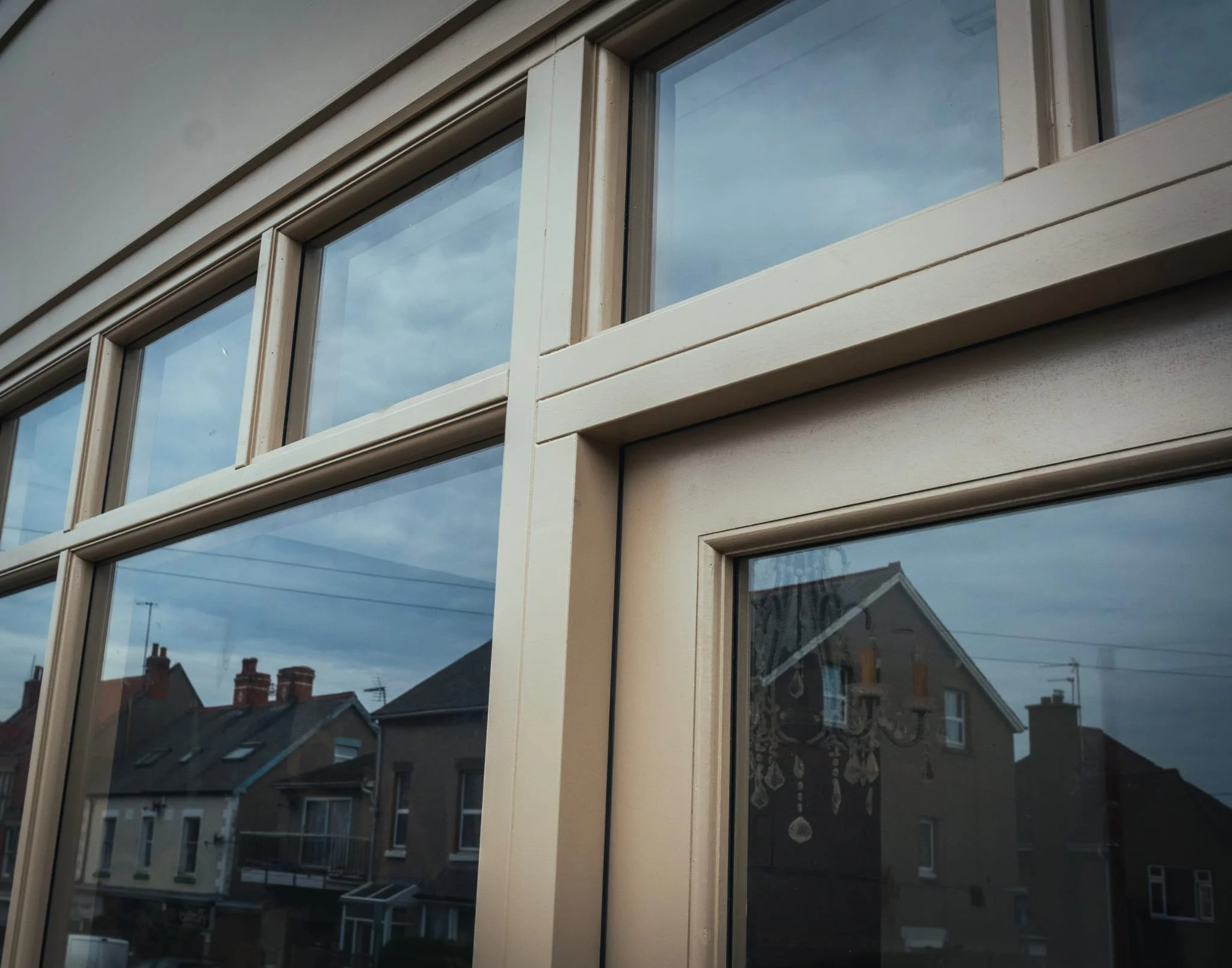Looking up at a residential building, view of windows with reflections of neighboring houses and cloudy sky. in rhos on sea 