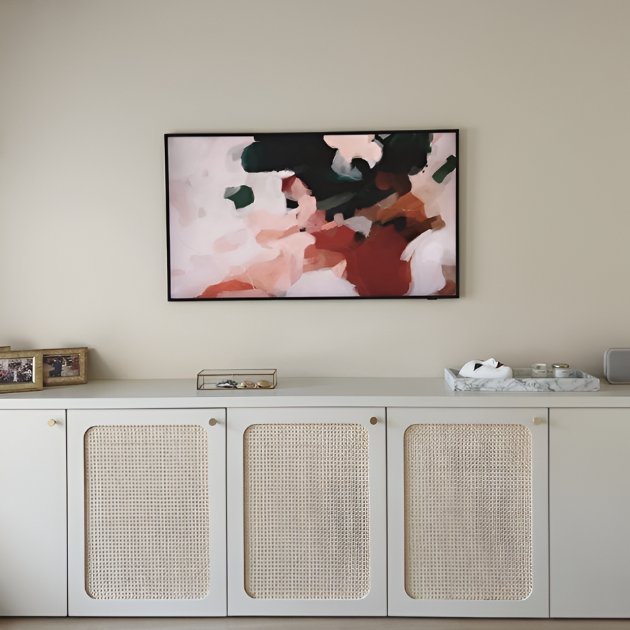 Un meuble blanc avec des portes en rotin, une décoration minimaliste, un tableau abstrait au mur, et quelques objets décoratifs dessus.
