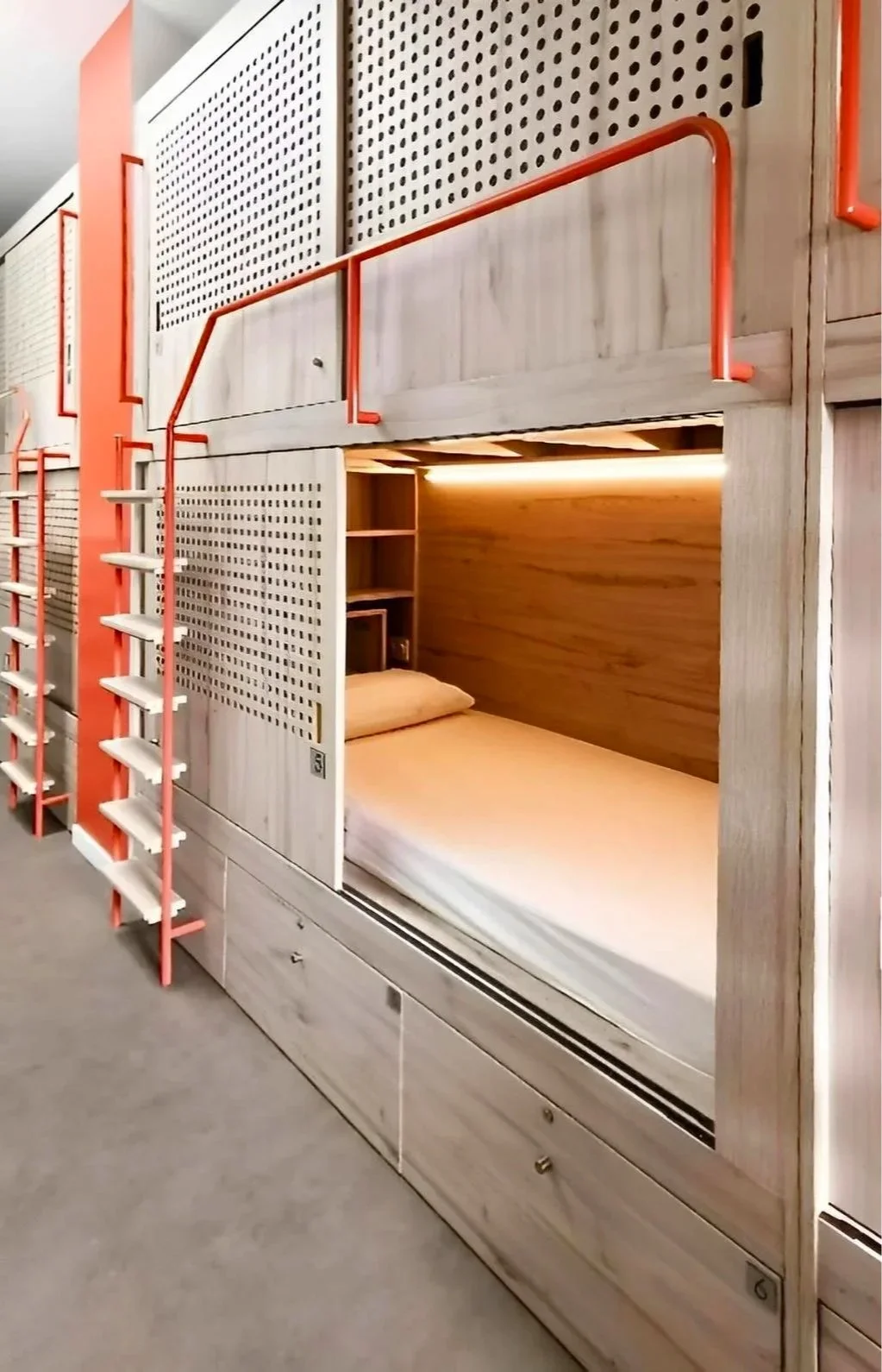 Lits superposés avec escaliers en bois et structure en métal orange dans une chambre.