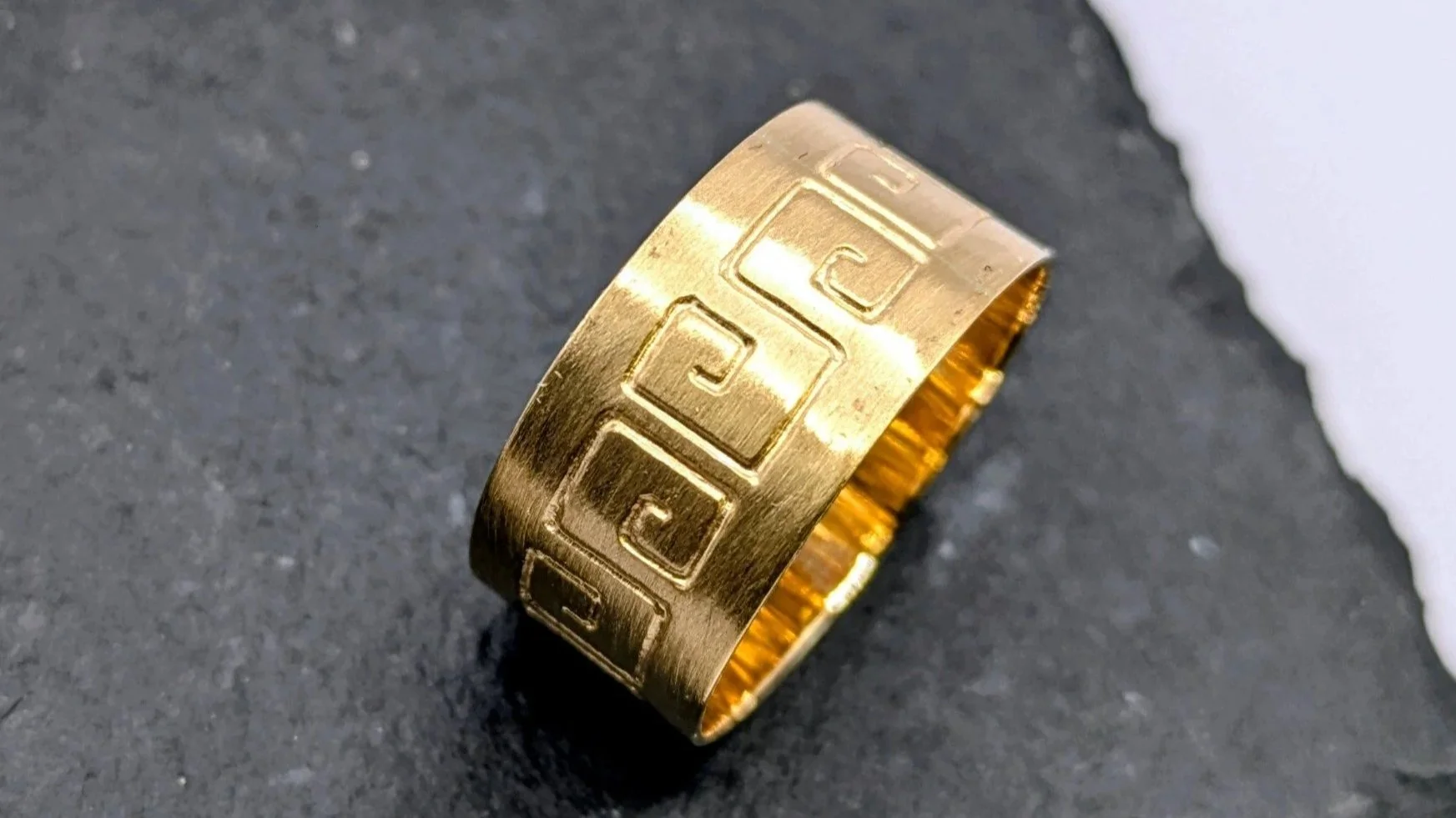 Greek ring. An 18ct gold wide band with greek-style hand engraving.