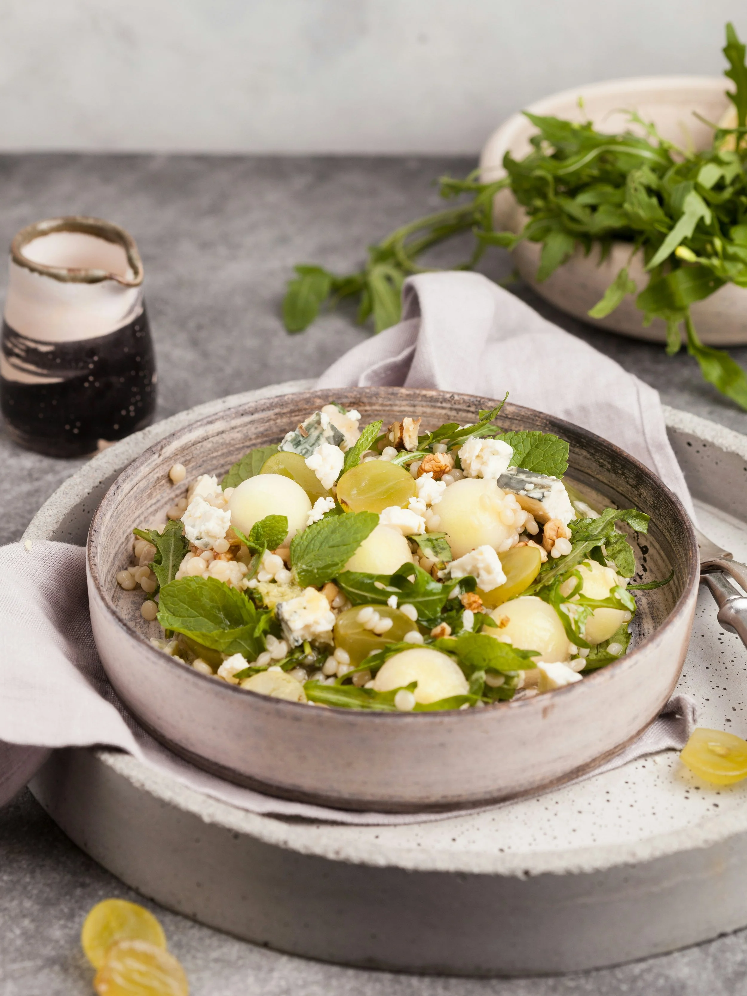 Salad with melon, feta, grapes, nuts, mint, and seeds in a bowl, decorated with mint leaves.