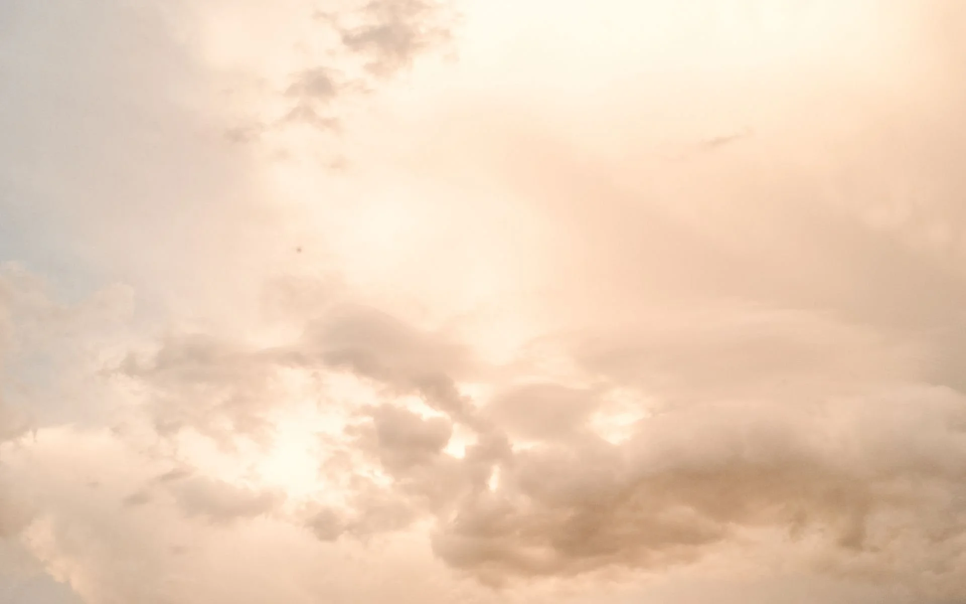 Cloudy sky with sunlight filtering through the clouds, creating a warm glow.