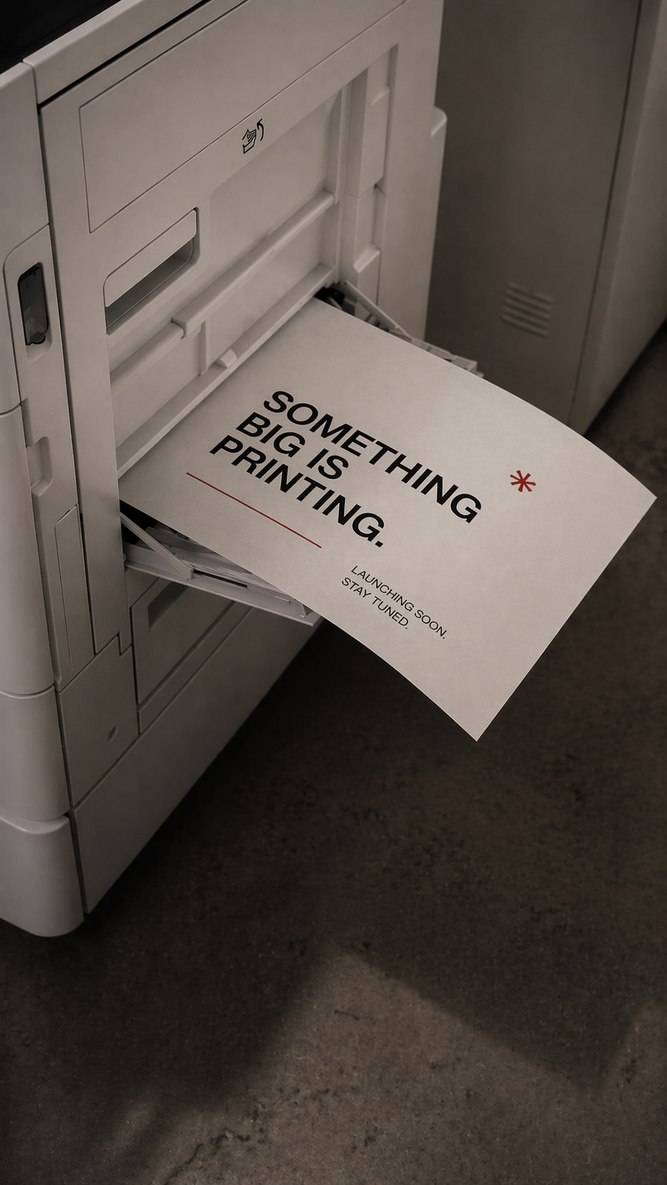 A printer printing a sign that reads 'Something Big Is Printing' with smaller text 'Launching Soon. Stay Tuned.'