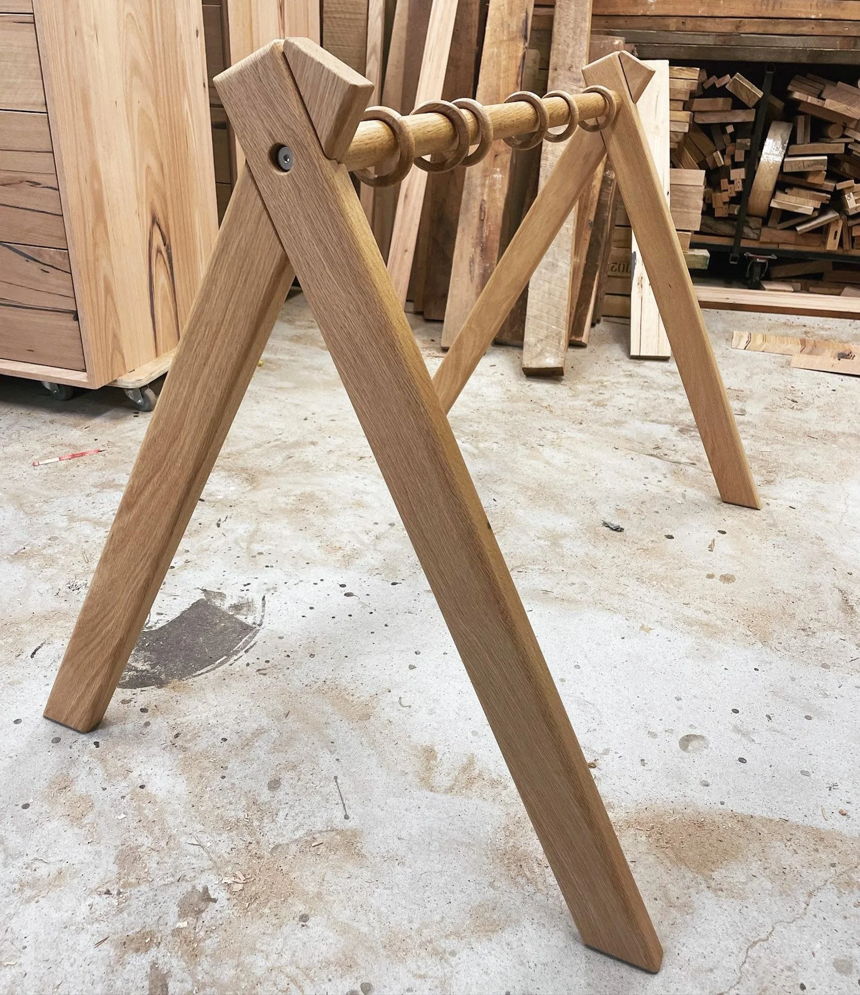 Wooden sawhorse in a woodworking shop with various pieces of wood stored in the background.