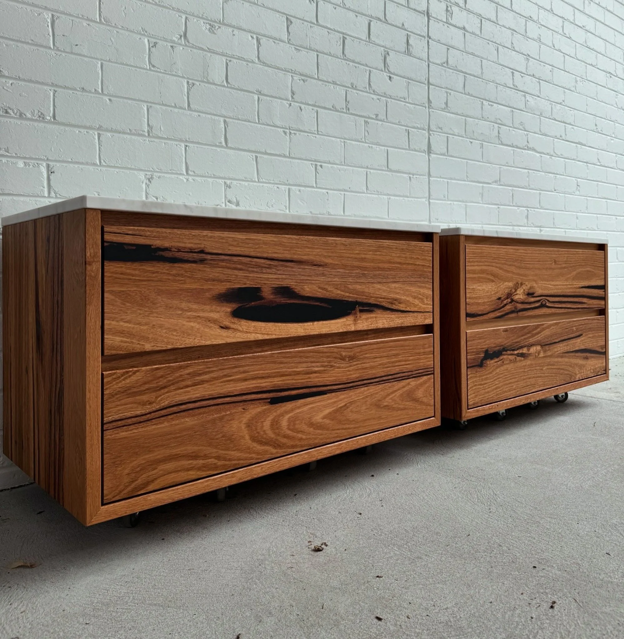 Timber vanity with a white stone top against a white brick wall, placed on a concrete floor.