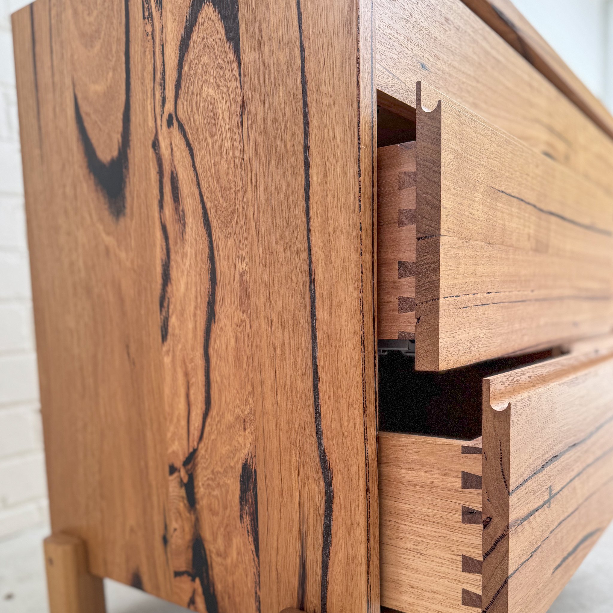 Close-up view of a wooden piece of furniture with a dovetail joint, emphasizing the wood grain and craftsmanship.