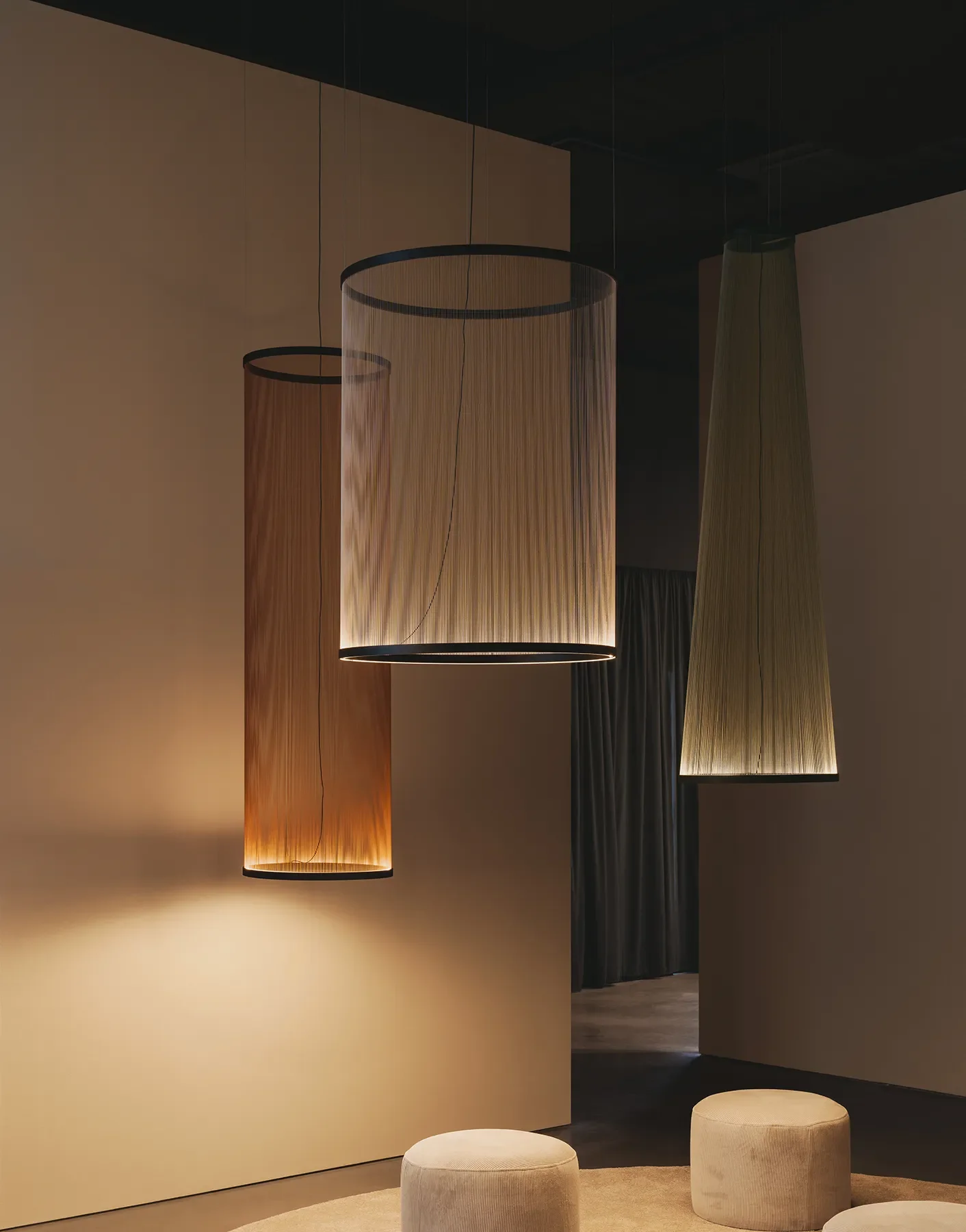 Luci di design appese al soffitto in una stanza moderna con pareti beige e sedute rotonde beige