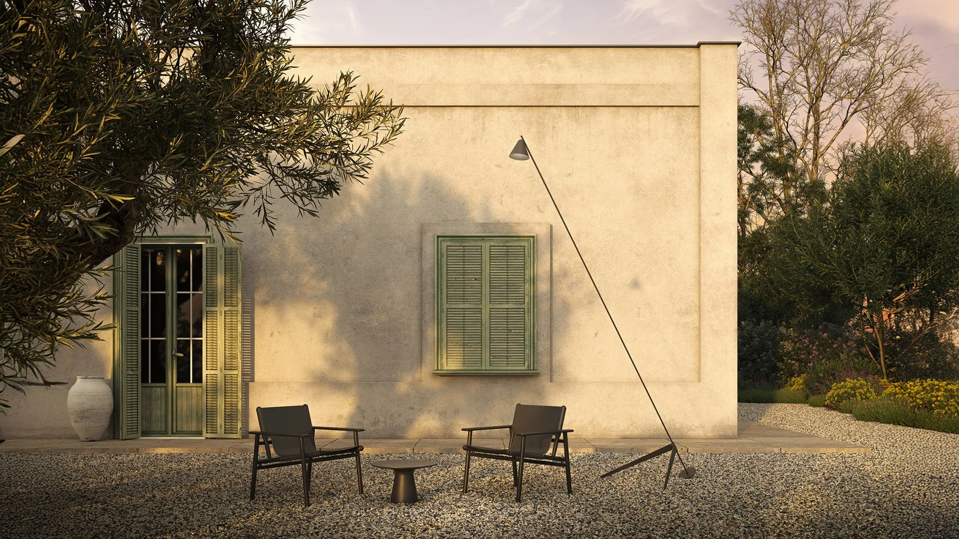 Patio con tre sedie e un tavolino, una parete beige con due finestre con imposte verdi, piante e alberi intorno, lampada da esterno inclinata