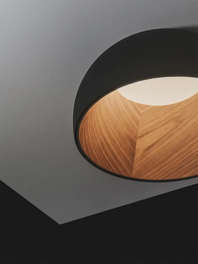 L'immagine mostra un soffitto con un'originale lampada rotonda con interno in legno e bordo nero.