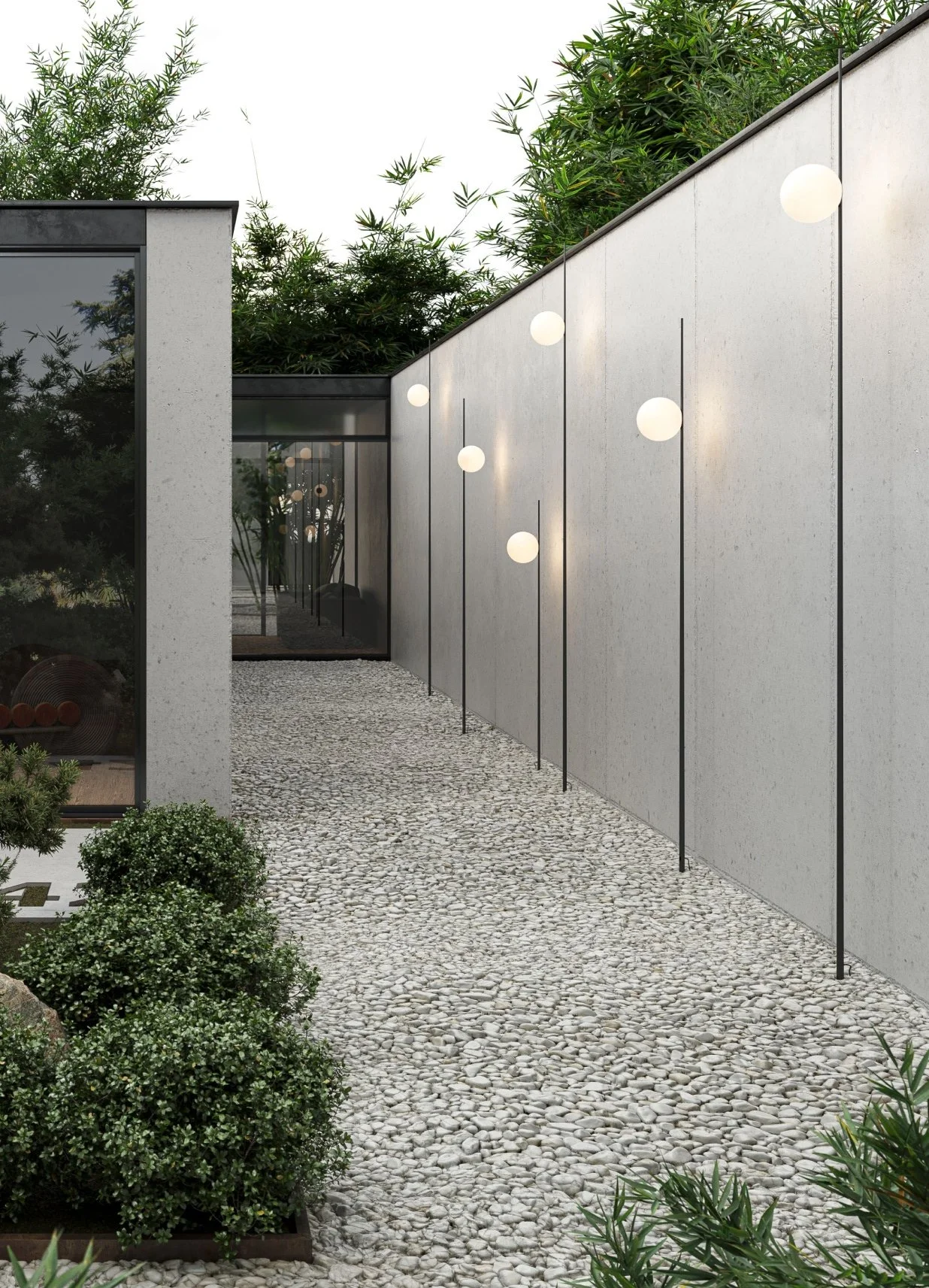 Un percorso pavimentato con ciottoli grigi accanto a un muro bianco decorato con lampade a sfera sospese e circondato da piante verdi e un edificio moderno con grandi finestre.