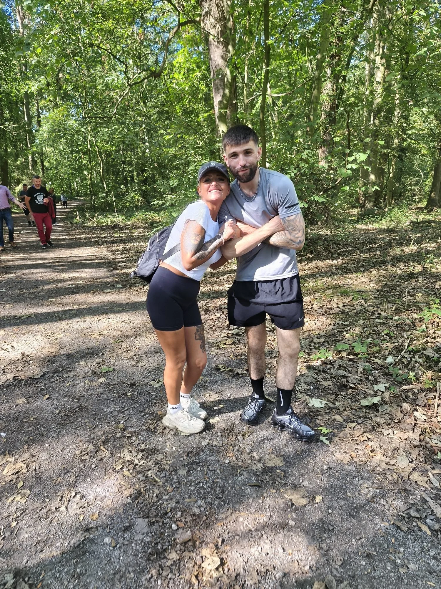Two walkers smiling for the camera on the woodland path during the Recovery Walk