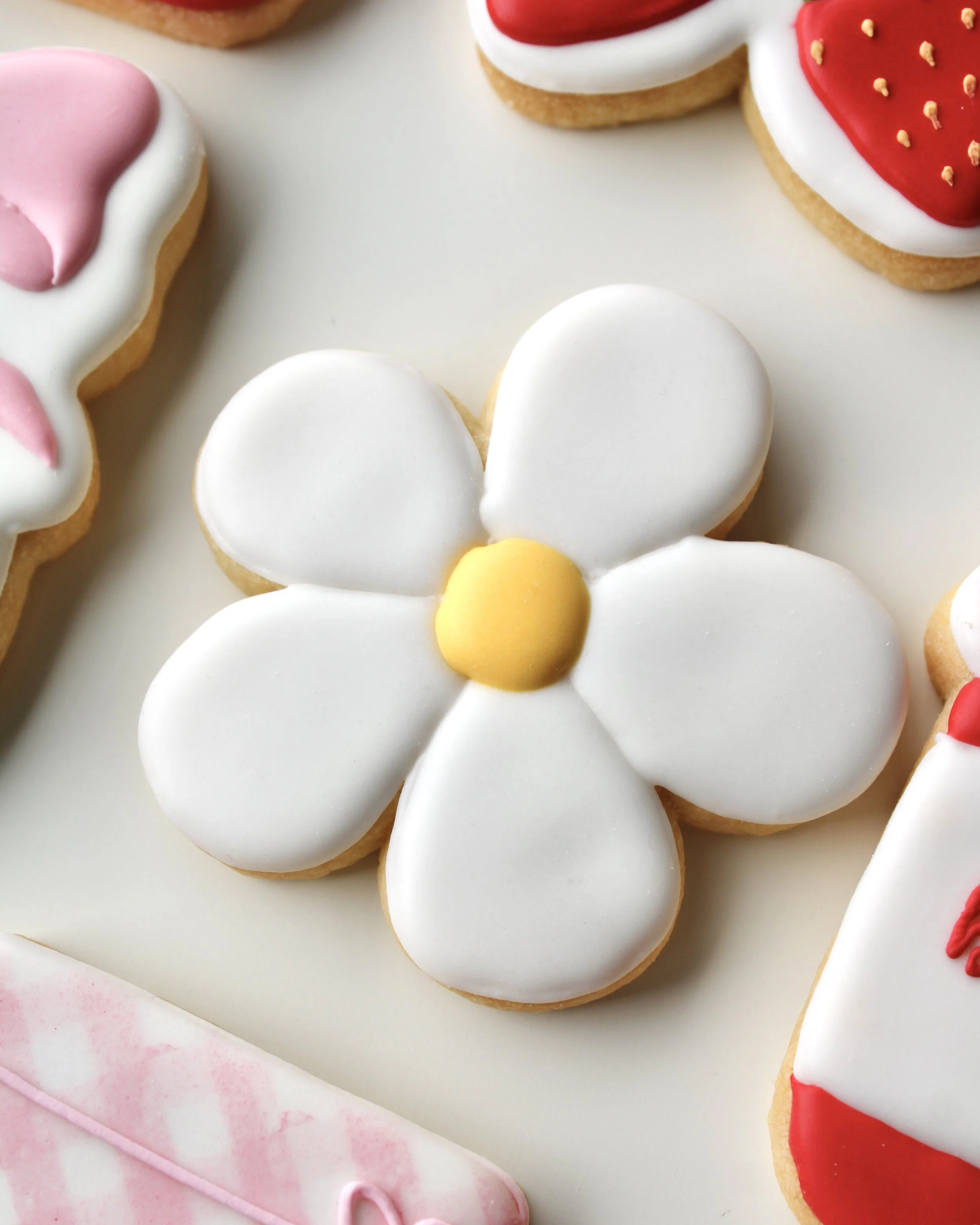 Close-up of daisy-shaped cookie with white petals and a yellow centre.
