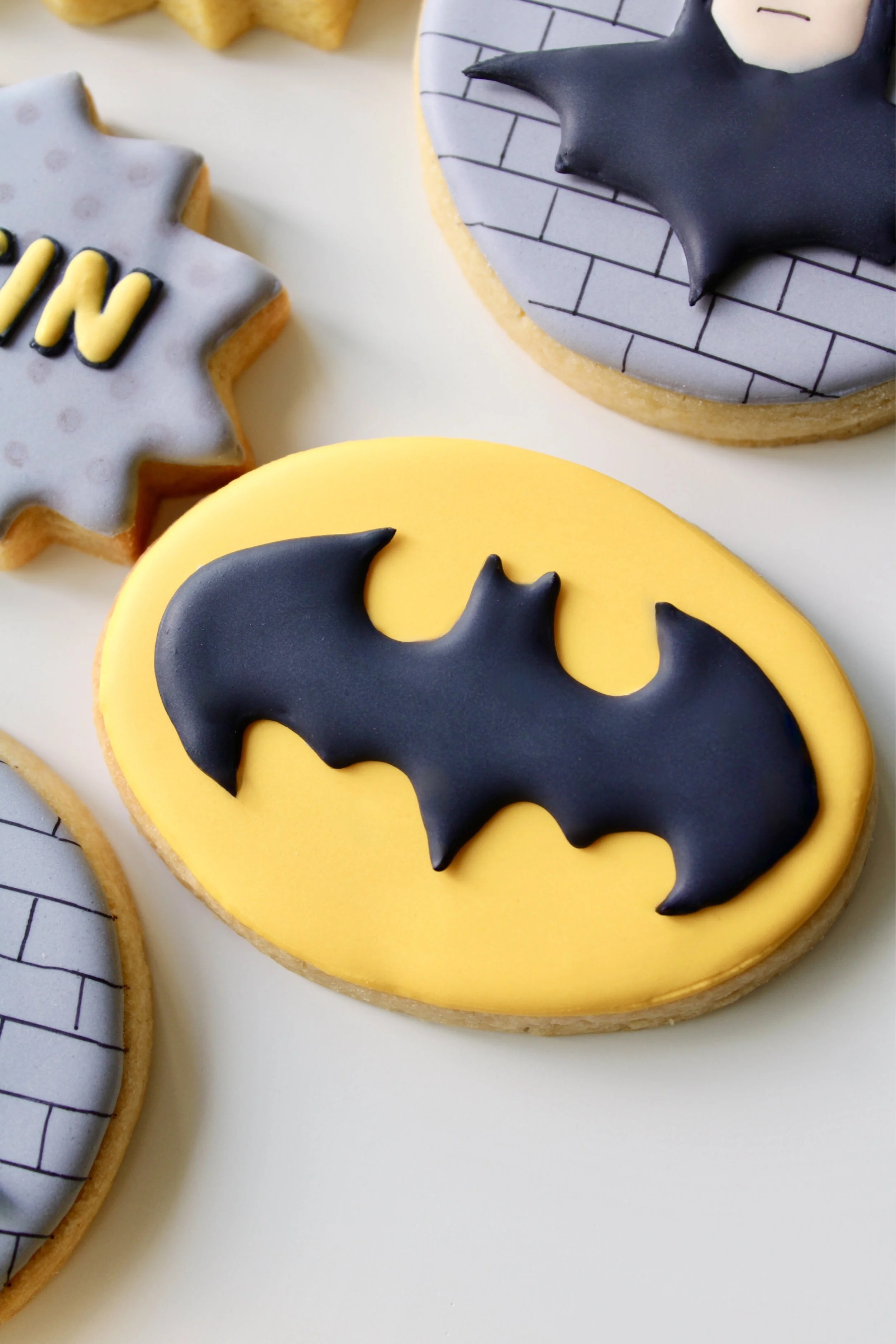 Close-up of oval Batman cookie with yellow icing and black bat symbol