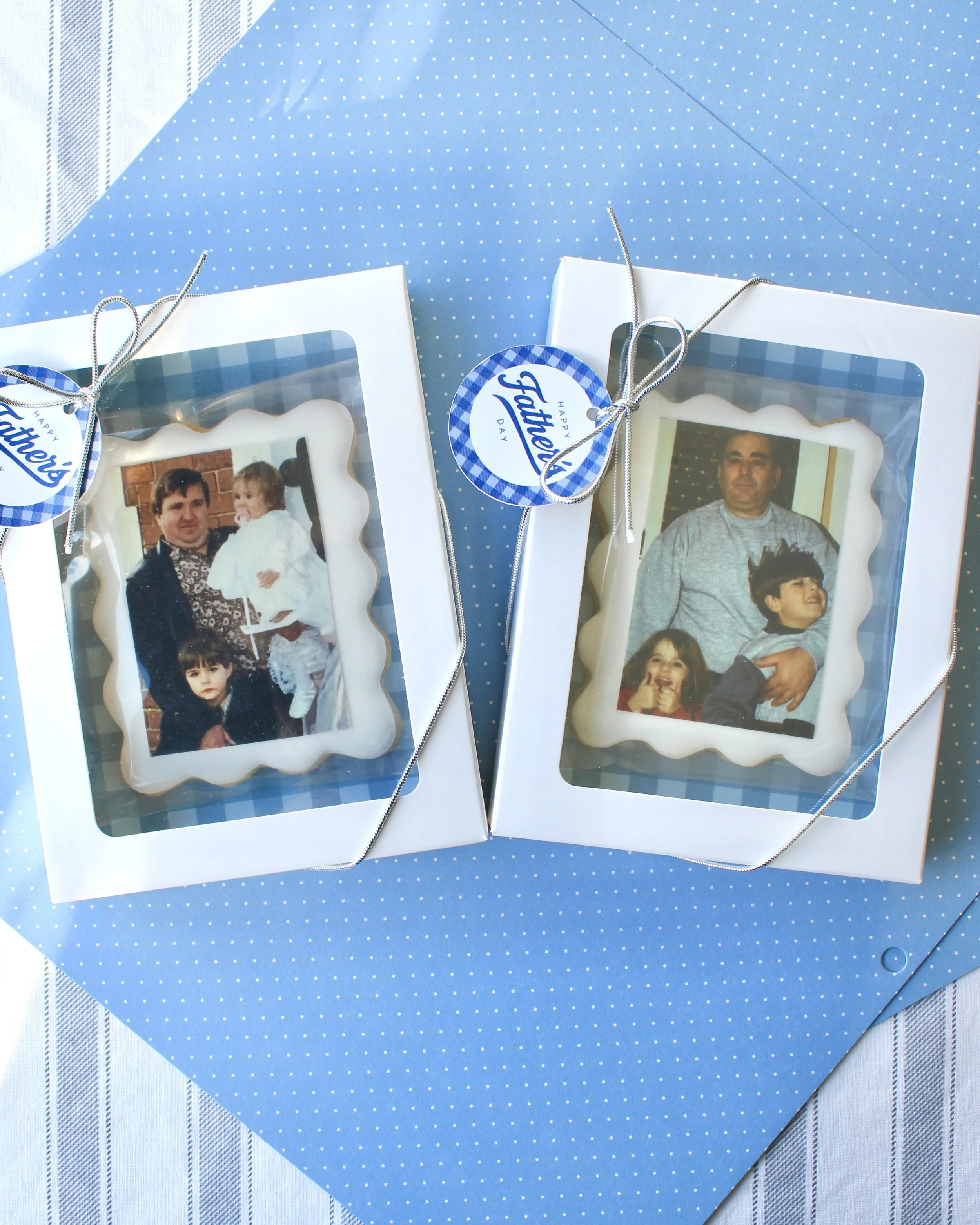 Two personalised Father’s Day photo cookie gift boxes with white iced cookies, wavy borders, printed photos, blue gingham backing, gift tags, and ribboned white boxes on a blue background.