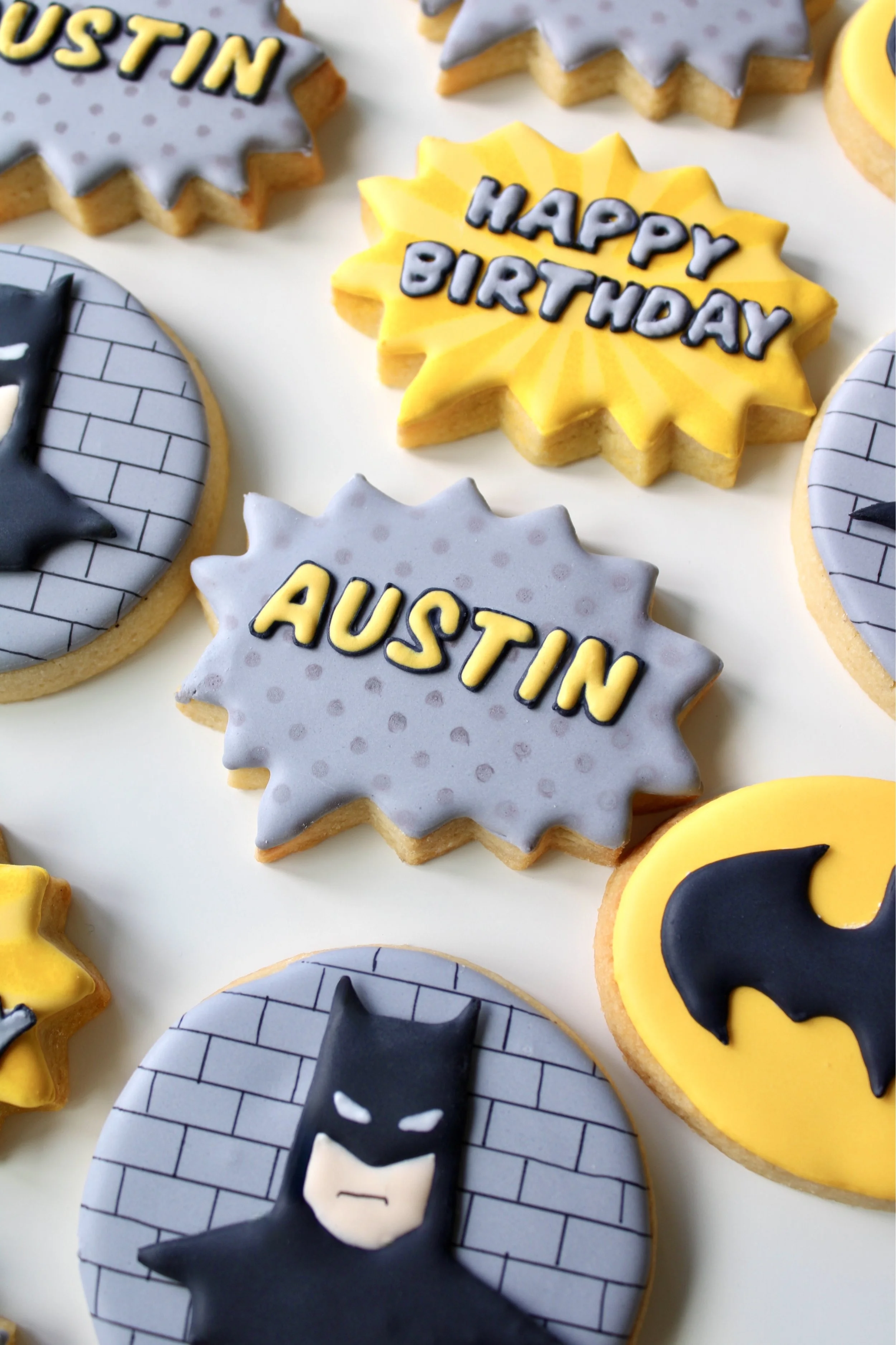 Close-up of grey and yellow personalised speech bubble cookie with the name Austin in comic-style lettering