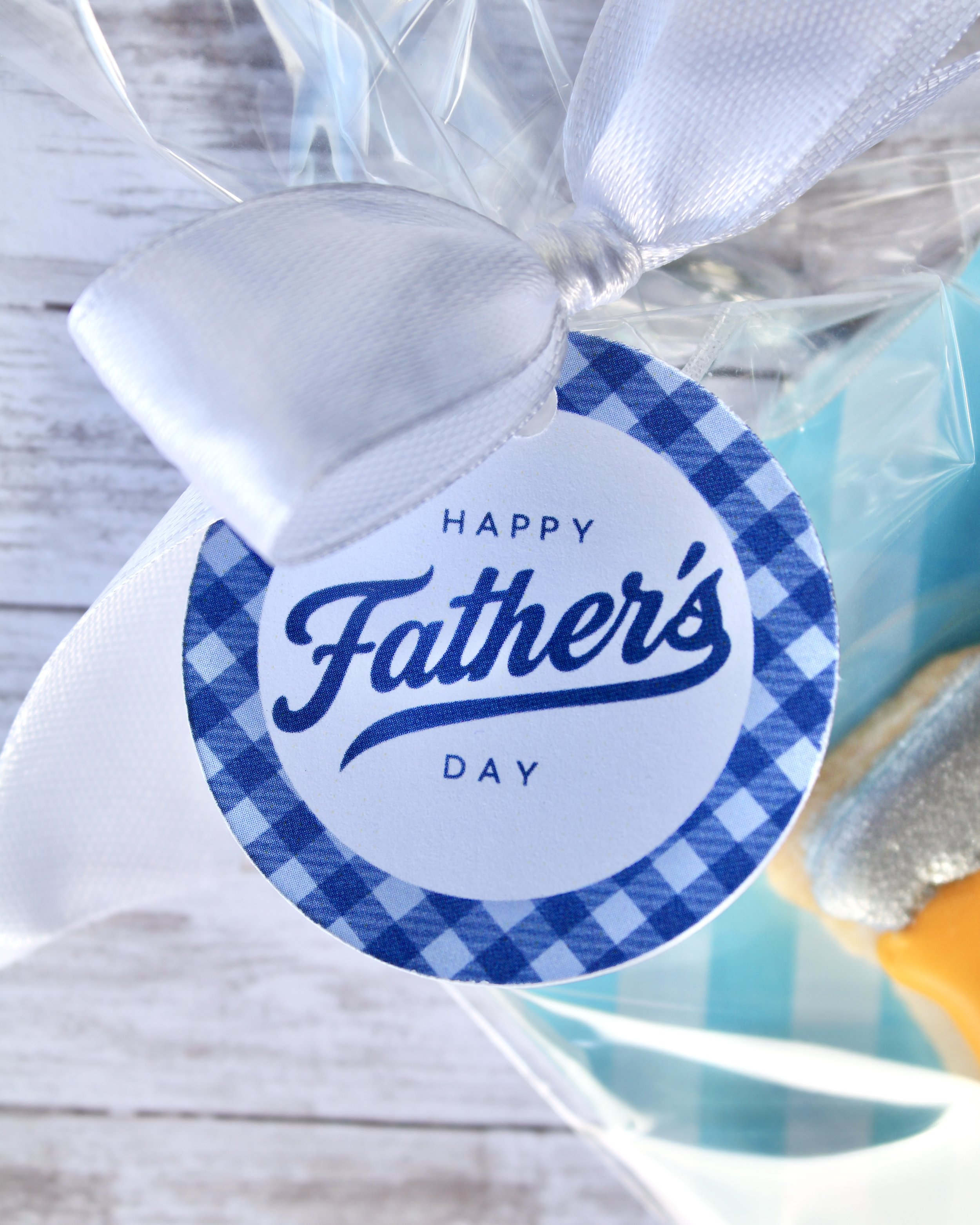 Close up of Happy Father's Day round gift tag tied around cookie gift with a white ribbon.