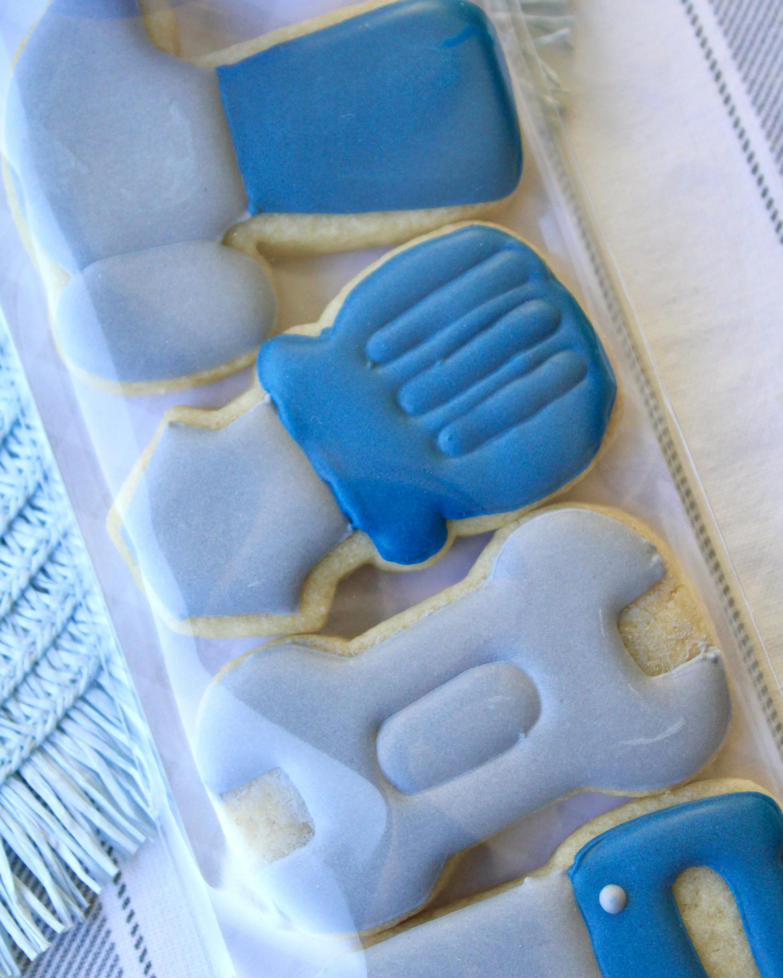Father’s Day cookie pack with mini tool-shaped sugar cookies including a hammer, screwdriver, wrench, saw and pliers in grey and blue, packaged with a white bow and Happy Father’s Day gift tag.
