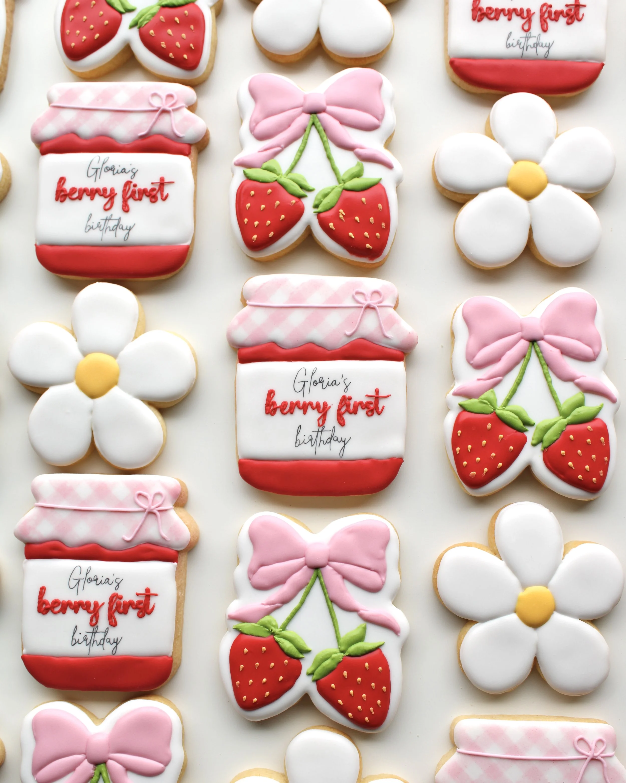 Berry first birthday themed cookie set featuring pink gingham patterns, strawberries, daisies, and bow details.