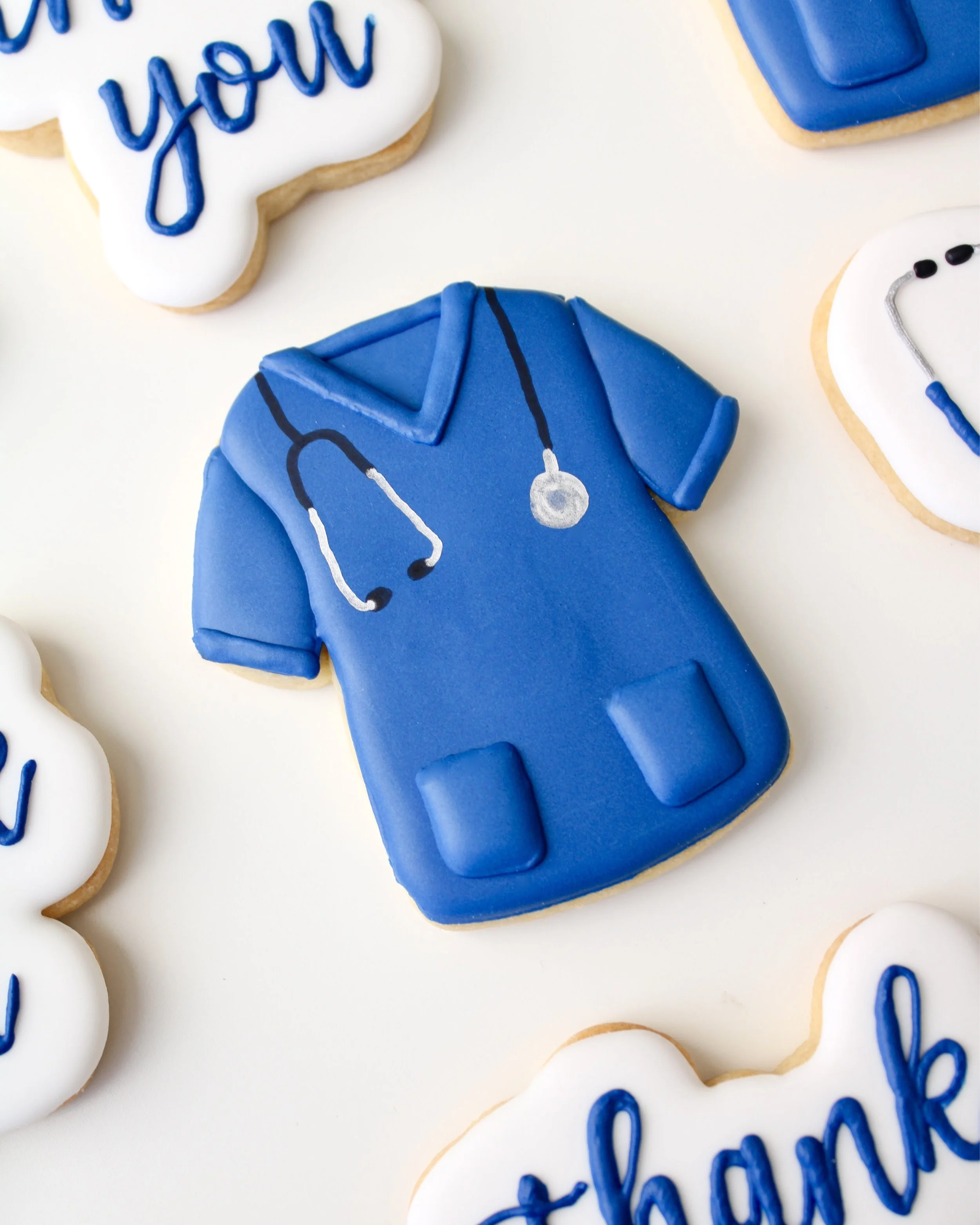 Close-up of a blue doctor and nurse scrub cookie with a black and silver stethoscope around the neck.
