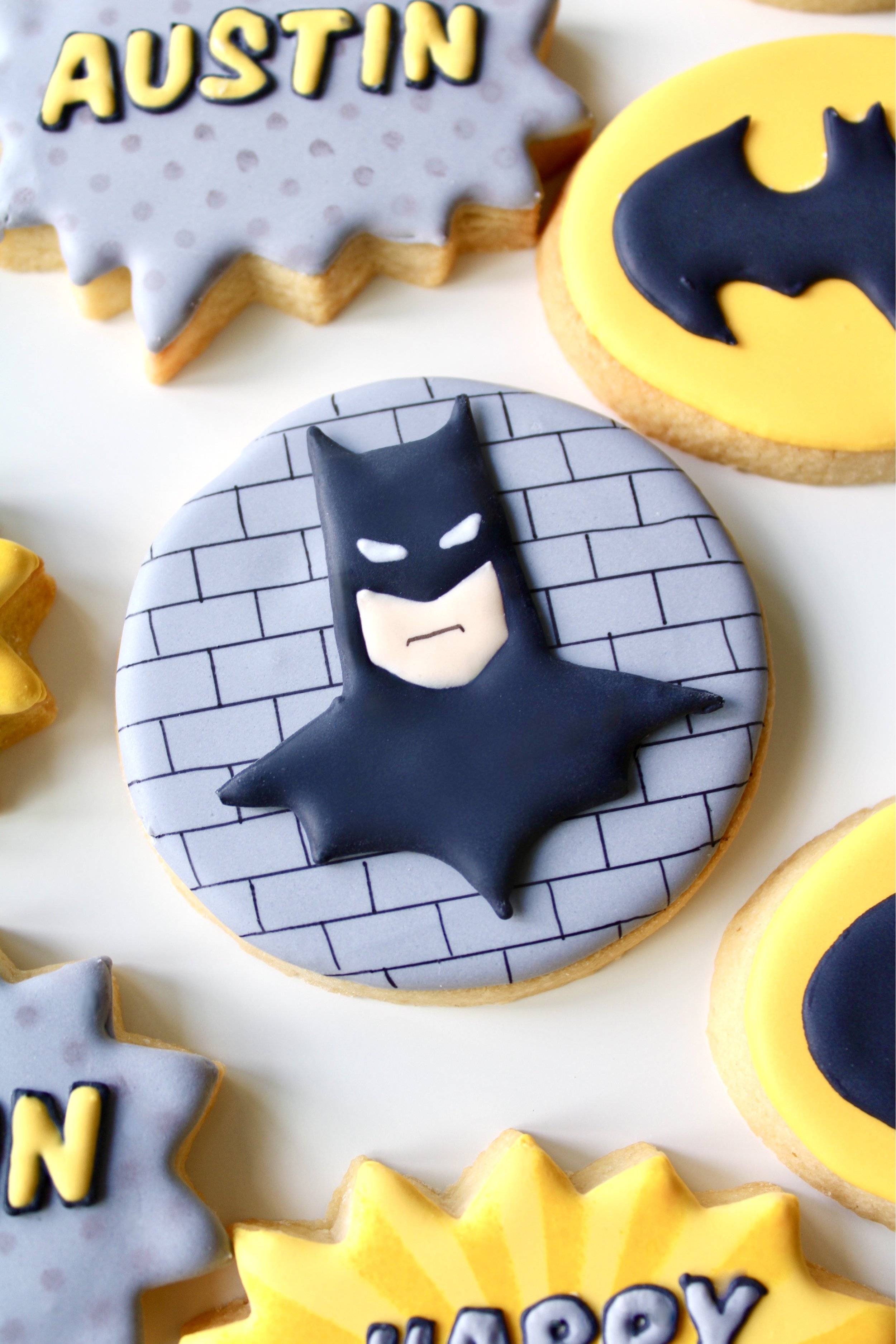 Close-up of grey round Batman cookie with brick detailing and Batman bust design
