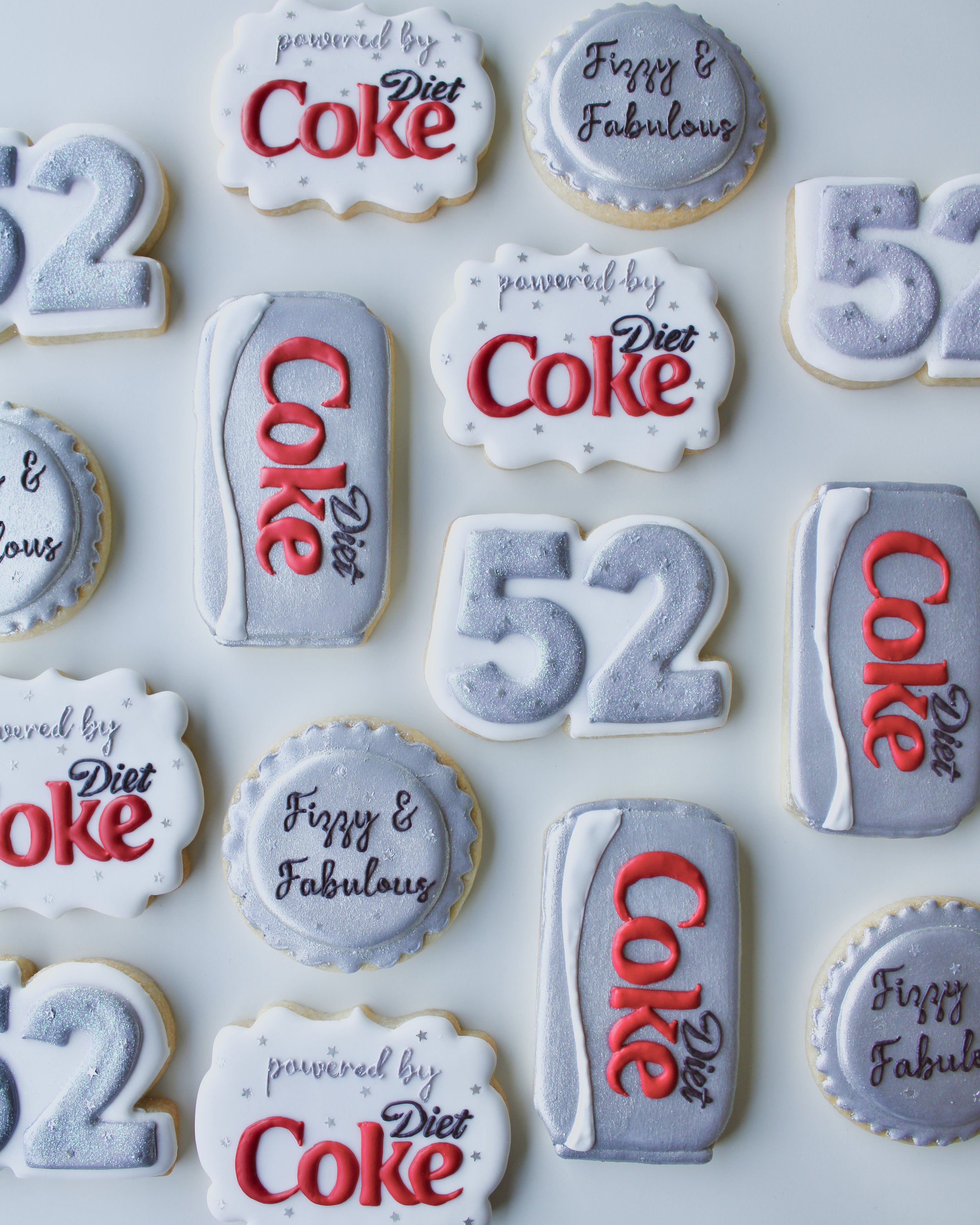 Diet Coke themed birthday cookies in silver, white and red accents, featuring Diet Coke cans and bottle cap designs.