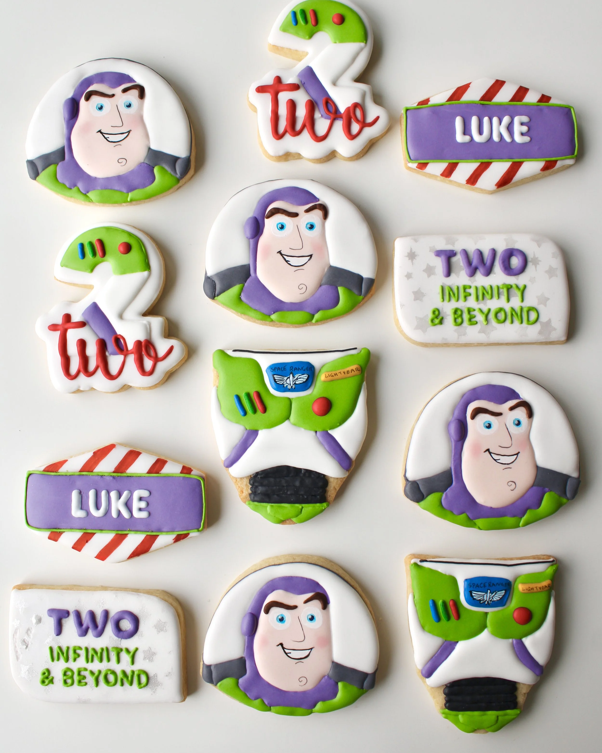 Toy Story Buzz Lightyear-inspired royal icing birthday cookies with Buzz faces, suits, number 2s, name plaques and Two Infinity & Beyond plaques