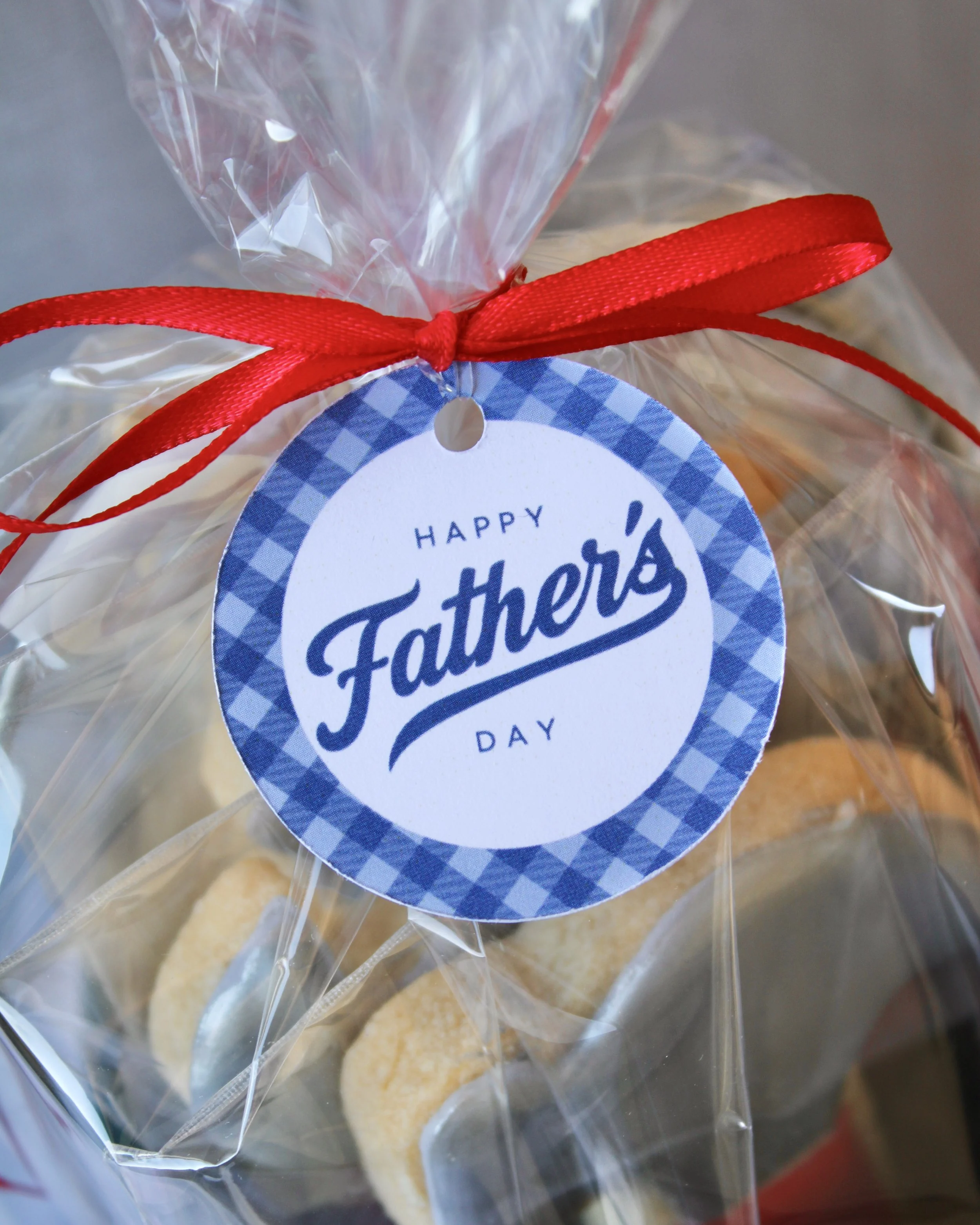 Close up of Happy Father's Day round gift tag tied around a tool cookie gift with a red ribbon.