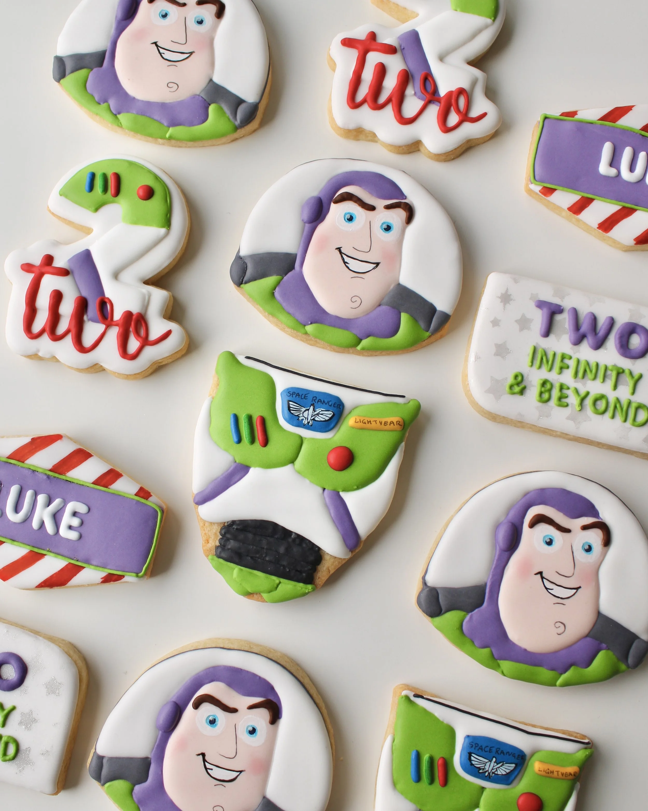 Toy Story Buzz Lightyear-inspired royal icing birthday cookies with Buzz faces, suits, number 2s, name plaques and Two Infinity & Beyond plaques