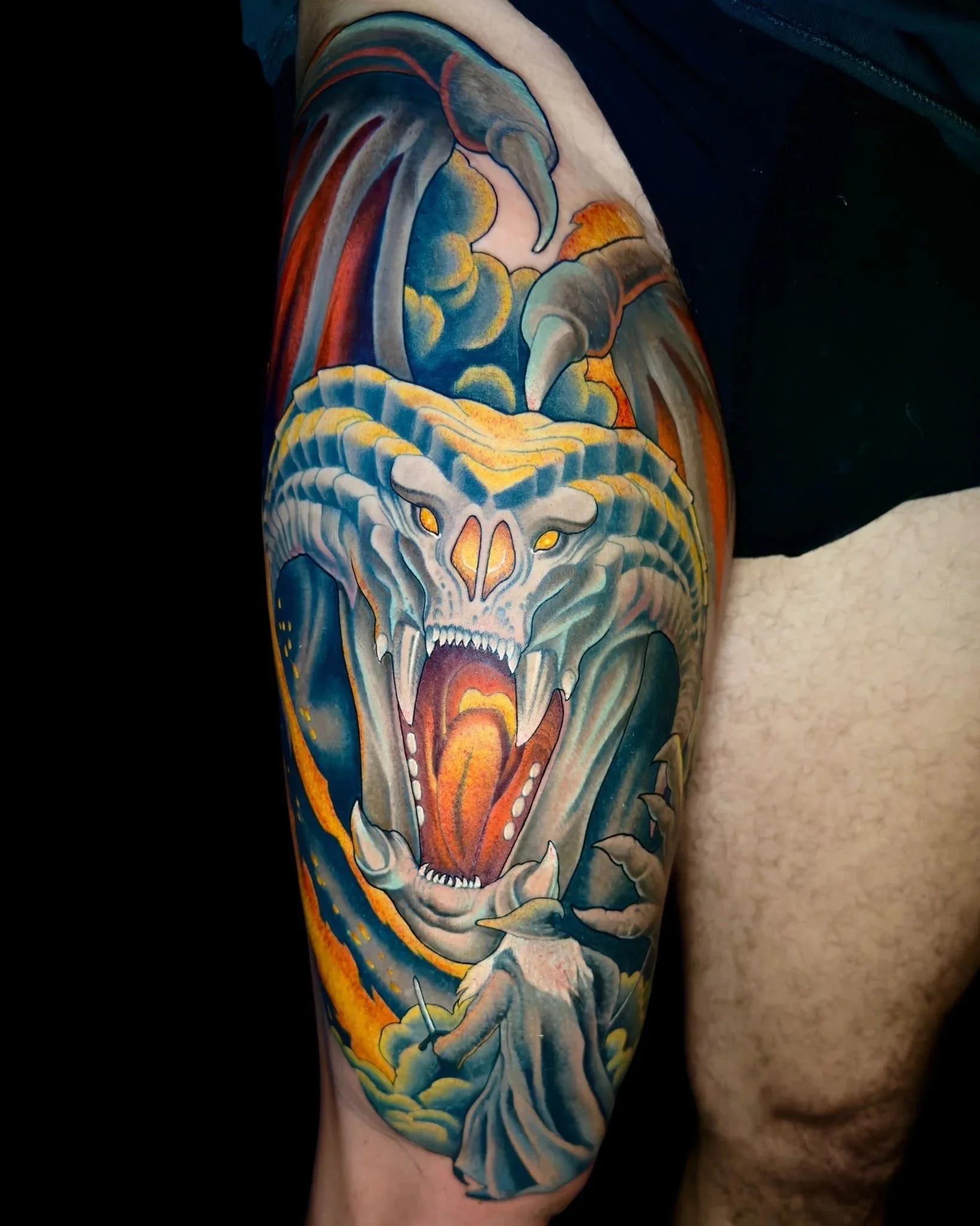 Fantasy skeletal dragon upper-arm tattoo with blue clouds and orange highlights by Chris Strik.