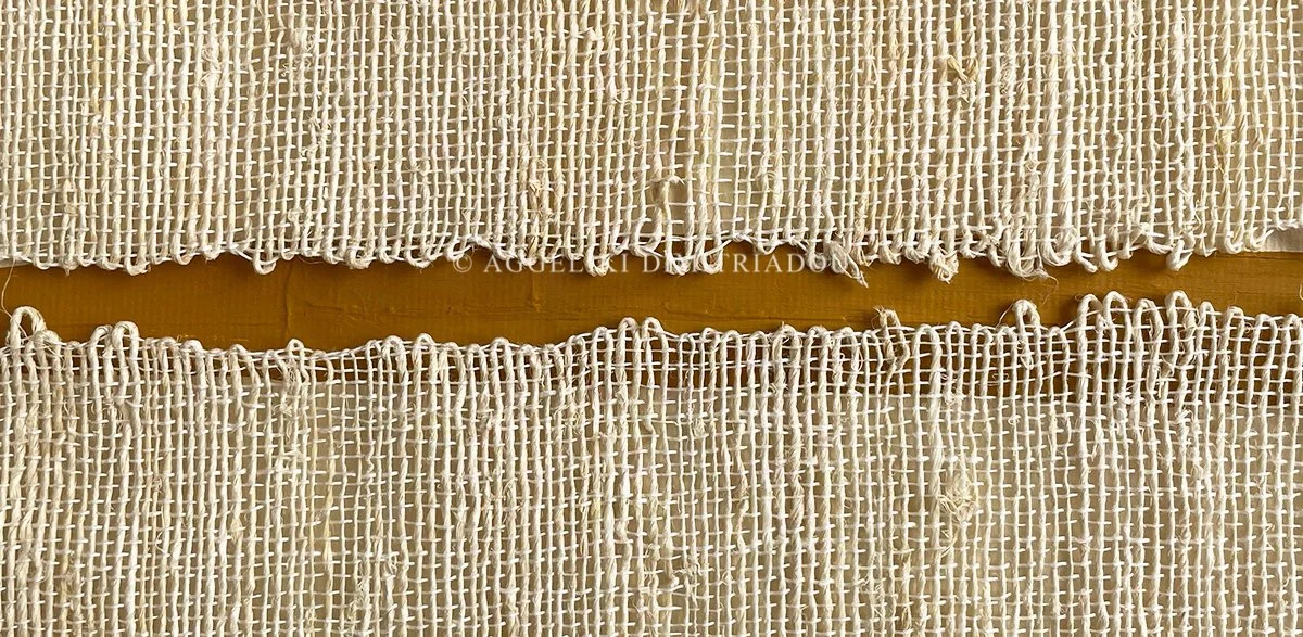 Close-up detail of handwoven natural fiber textile with a narrow painted gap in ochre yellow, from the Gaps series by Aggeliki Dimitriadou.