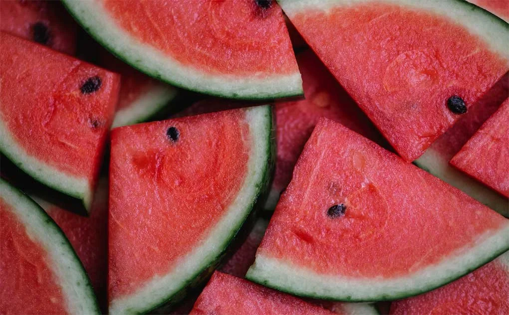 Close-up of sliced watermelons with red flesh, black seeds, and green rind.