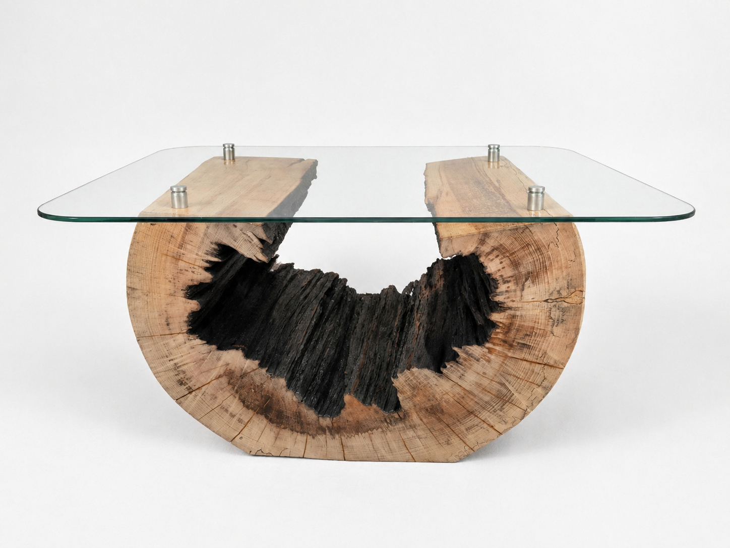 A modern table with a glass top and a base made from a large, semicircular piece of wood with a blackened center