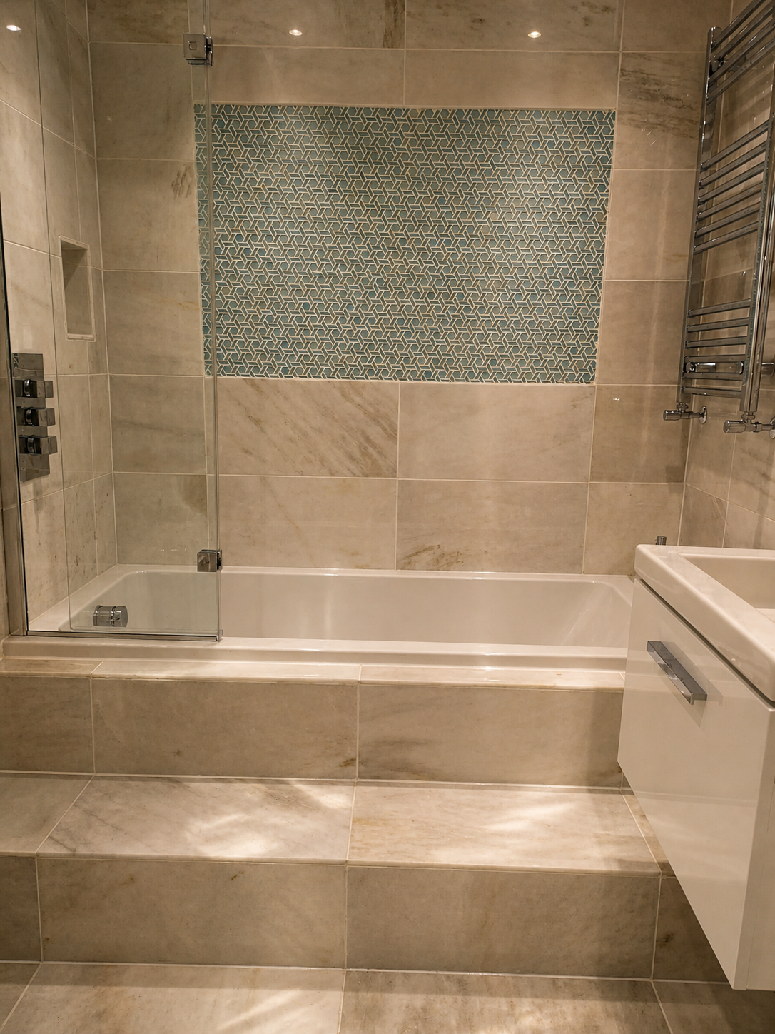 Bathroom with beige tiled walls and floor, glass shower partition, partial bathtub, and a white vanity with a sink.