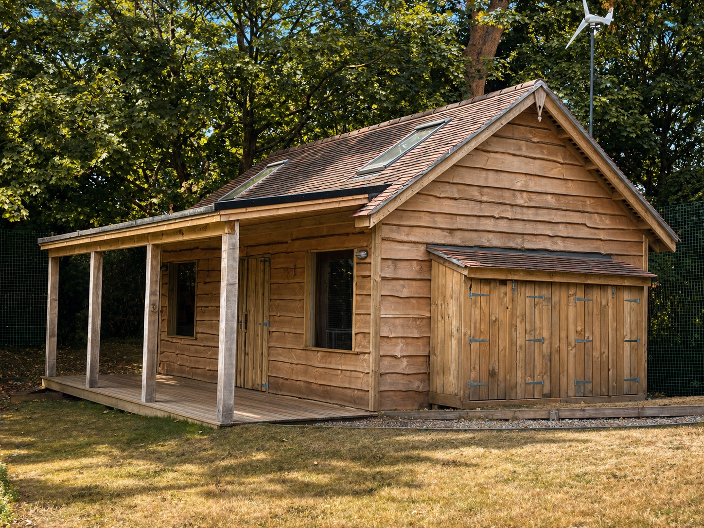 A small wooden house with a porch and a roof with two skylights, set in a yard with trees and grass.